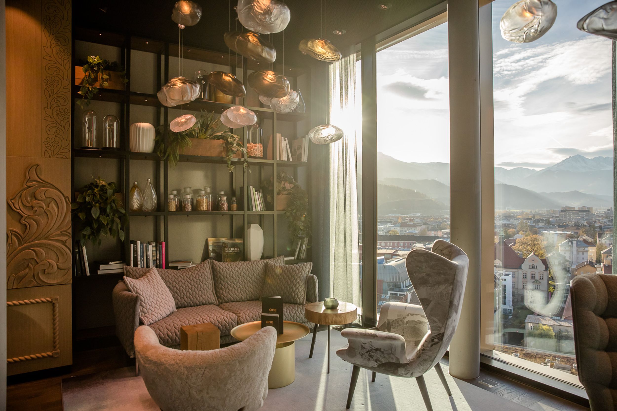Designhotel Innsbruck Motel One lichtdurchflutete Lounge mit Sesseln vor bodentiefer Fensterfront