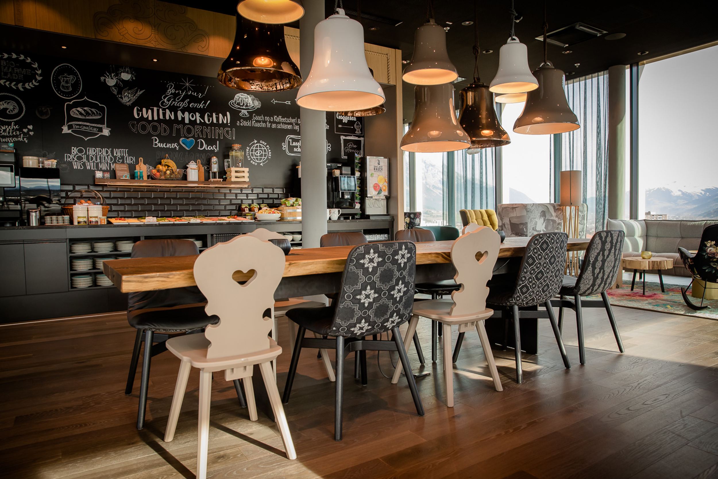 Designhotel Innsbruck Motel One Frühstücksbereich mit langem Tisch und Bergblick durch große Fensterfront