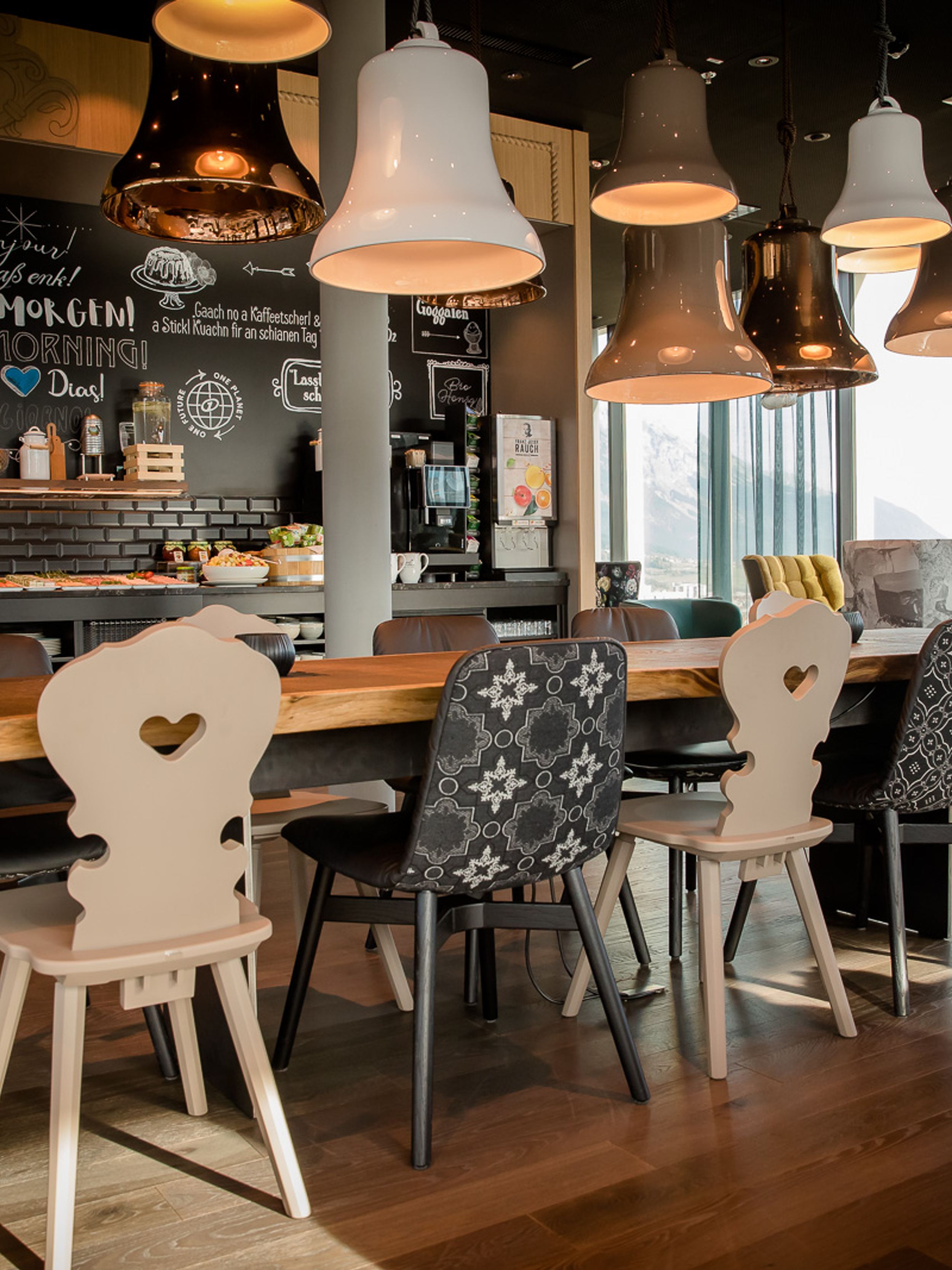 Designhotel Innsbruck Motel One Frühstücksbereich mit langem Tisch und Bergblick durch große Fensterfront