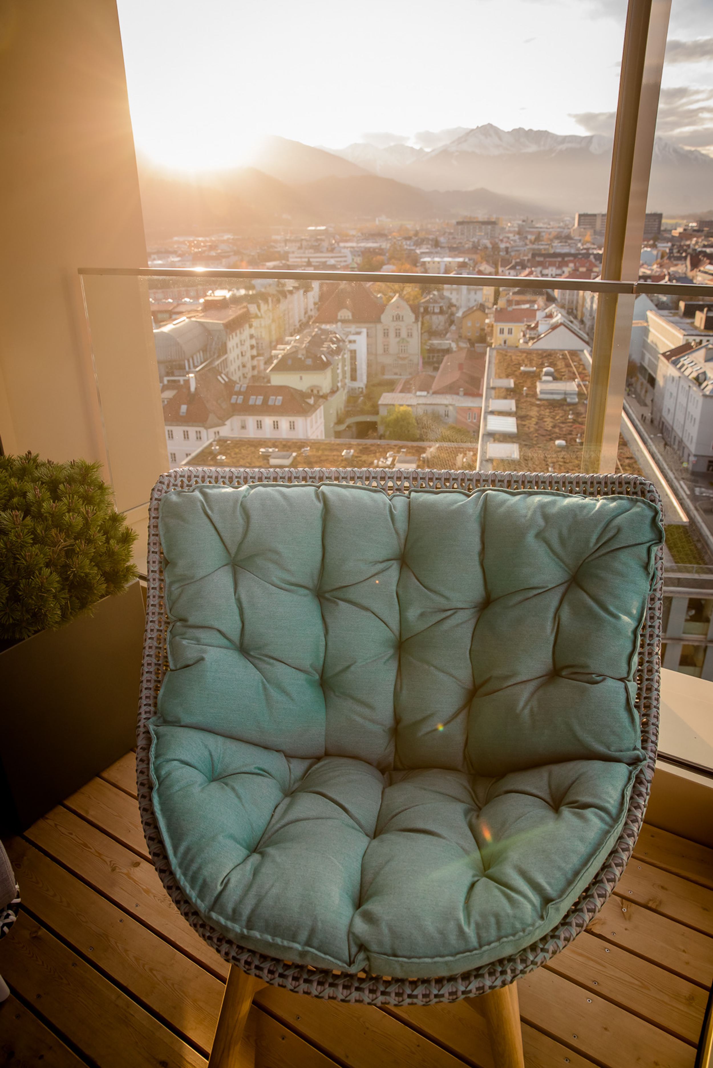 Designhotel Innsbruck Motel One Sessel vor bodentiefem Fenster mit Blick auf Berge und Stadt