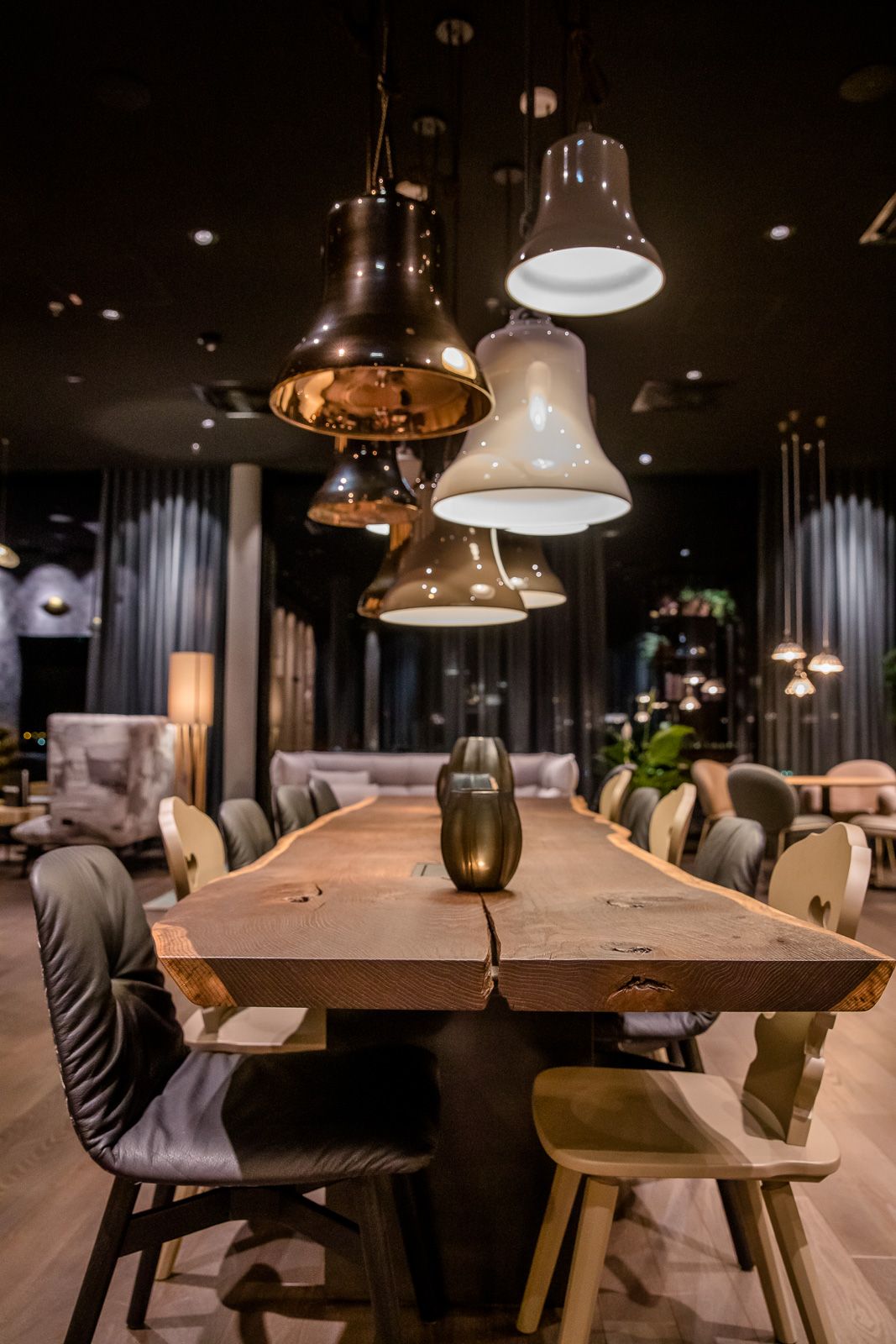 Designhotel Innsbruck Motel One langer Tisch mit mehreren Stühlen bei Abend mit mehreren Lampen