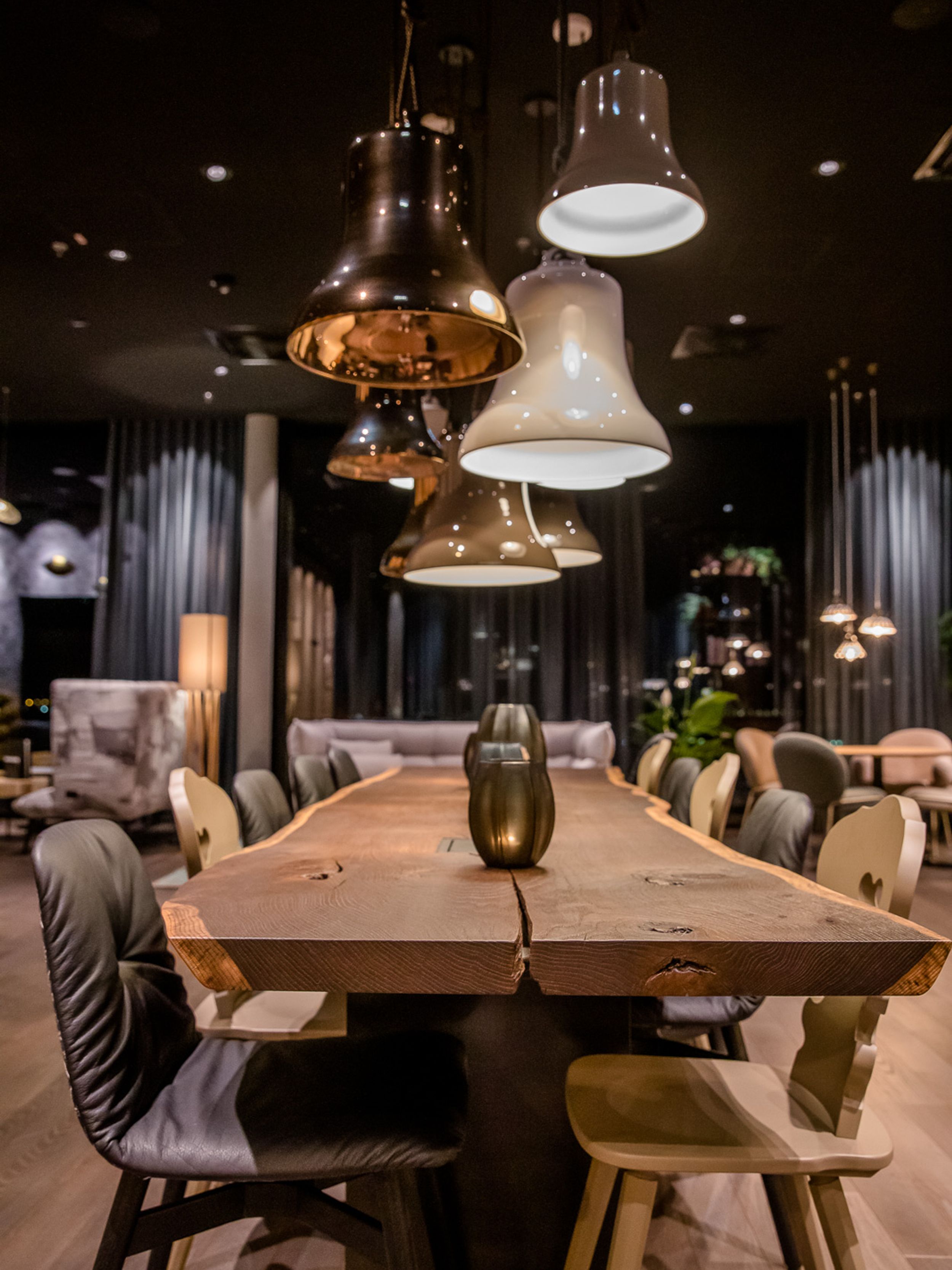 Designhotel Innsbruck Motel One langer Tisch mit mehreren Stühlen bei Abend mit mehreren Lampen