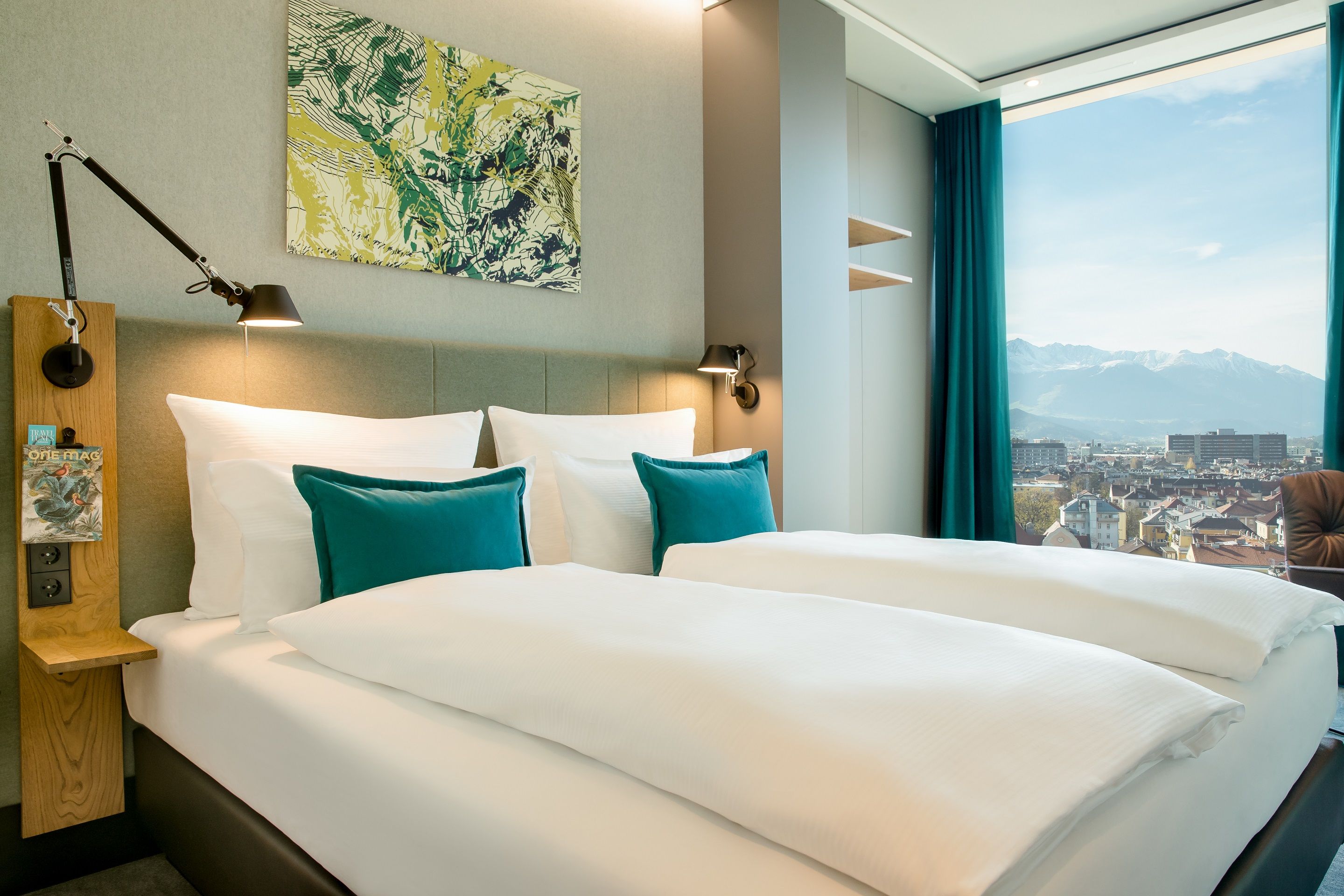 Hotel Innsbruck Motel One Blick auf großes Doppelbett sowie bodentiefes Fenster mit Panoramablick