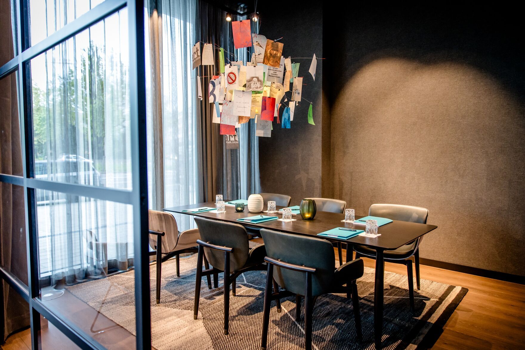 Hotel Karlsruhe Motel One Meetingraum mit Tisch, sechs Stühlen sowie bodentiefem Fenster für viel Licht