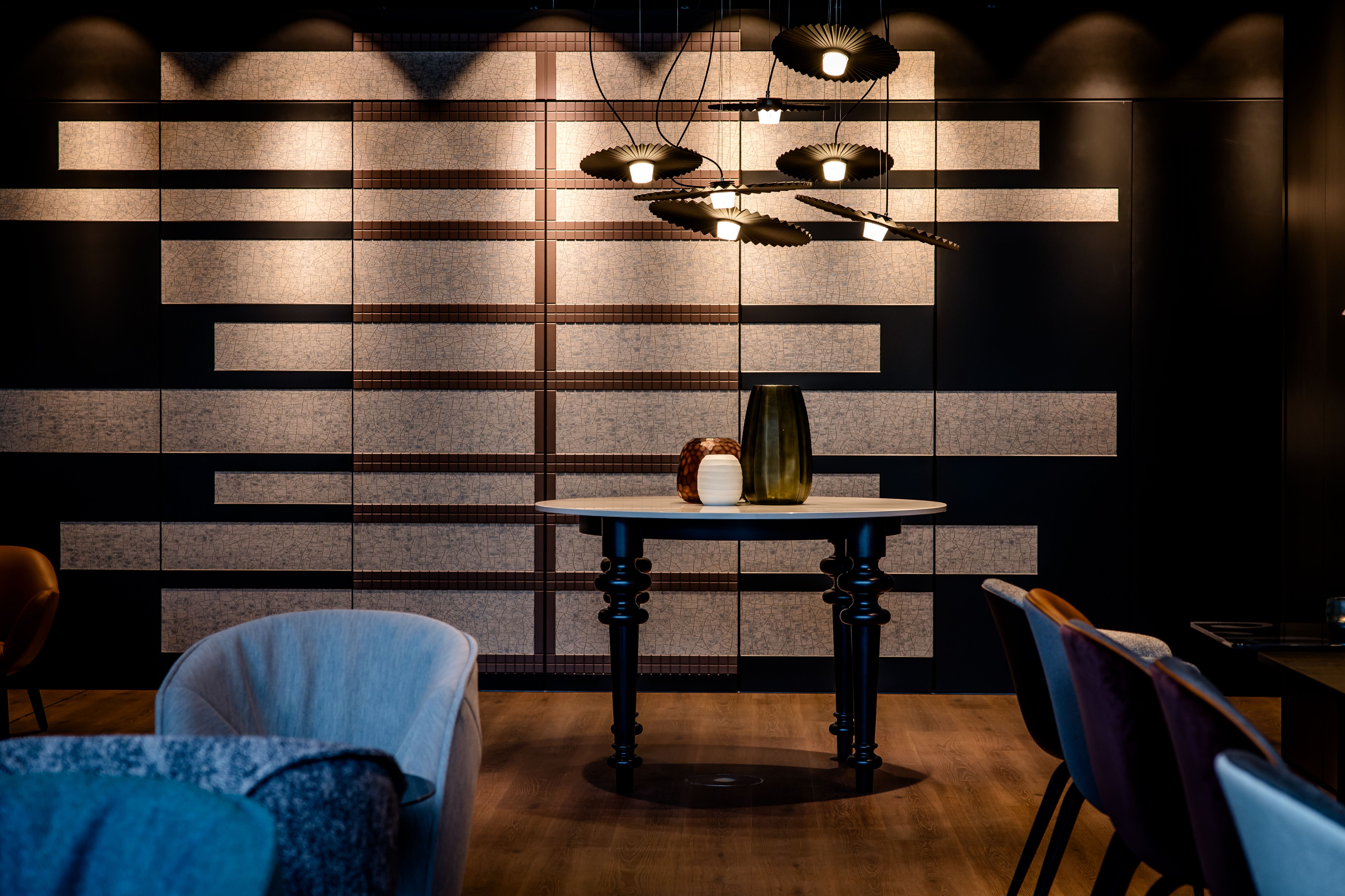 Hotel Karlsruhe Motel One Blick auf runden Tisch vor großer Wand sowie Stühle links und rechts vom Bild