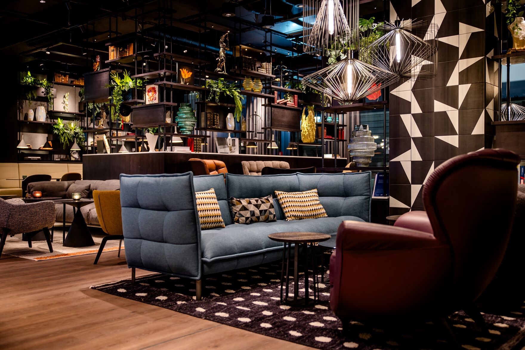 Hotel Karlsruhe Motel One große Lounge mit offenem Regal sowie mehreren Sitzgelegenheiten zum Vereilen