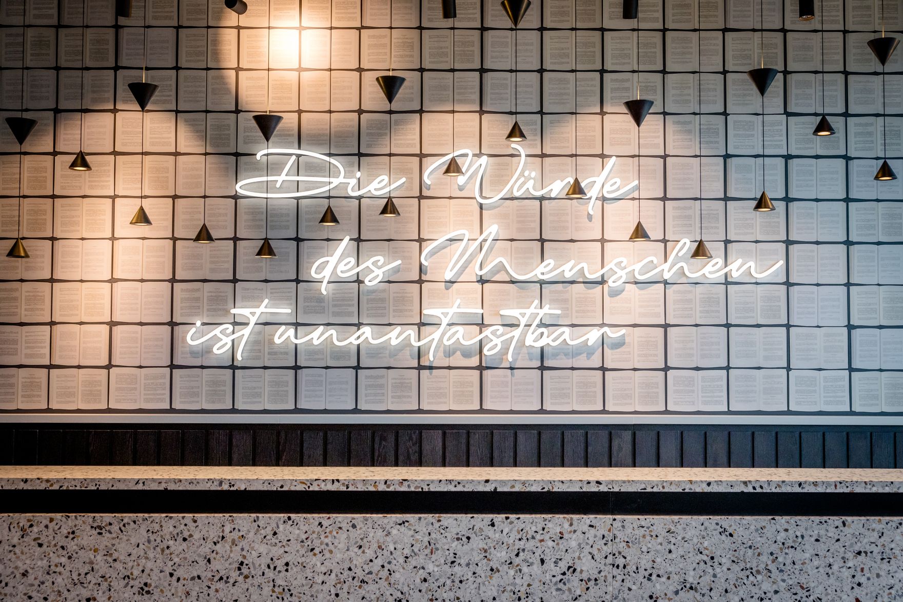 Hotel Karlsruhe Motel One Rezeption mit Gesetzestexten und großer Leuchtschrift "Die Würde des Menschen ist unantastbar"