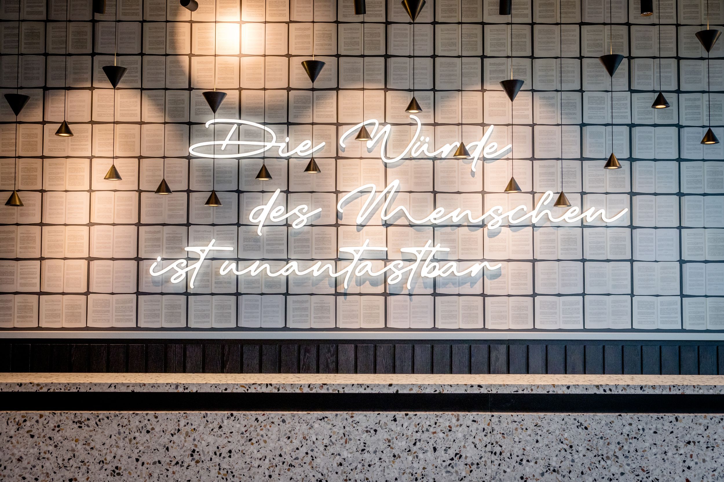 Hotel Karlsruhe Motel One Rezeption mit Gesetzestexten und großer Leuchtschrift "Die Würde des Menschen ist unantastbar"