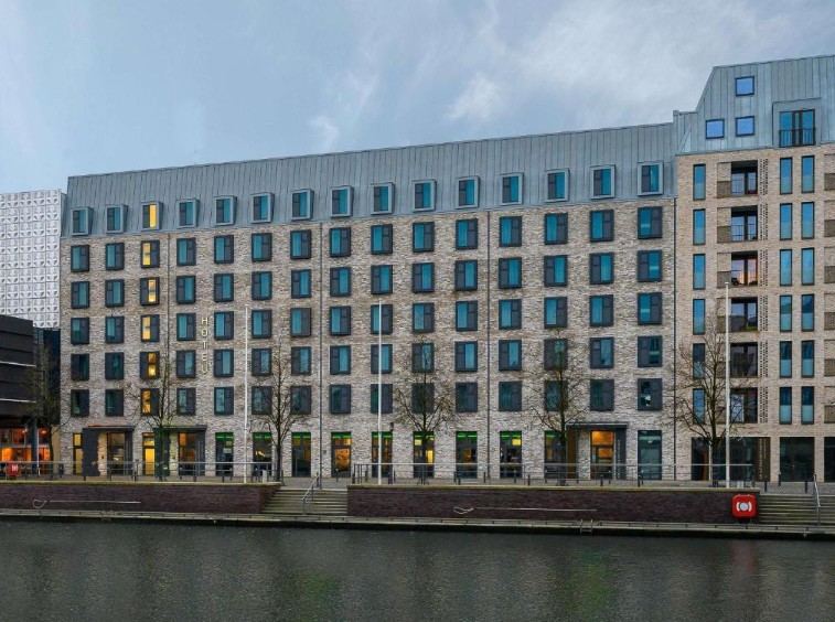 Hotel Kiel Schwedenkai Modernes Hotelgebäude mit zahlreichen Fenstern, direkt am Wasser gelegen, bei bewölktem Himmel. Hotel Kiel Schwedenkai Modernes Hotelgebäude mit zahlreichen Fenstern, direkt am Wasser gelegen, bei bewölktem Himmel.