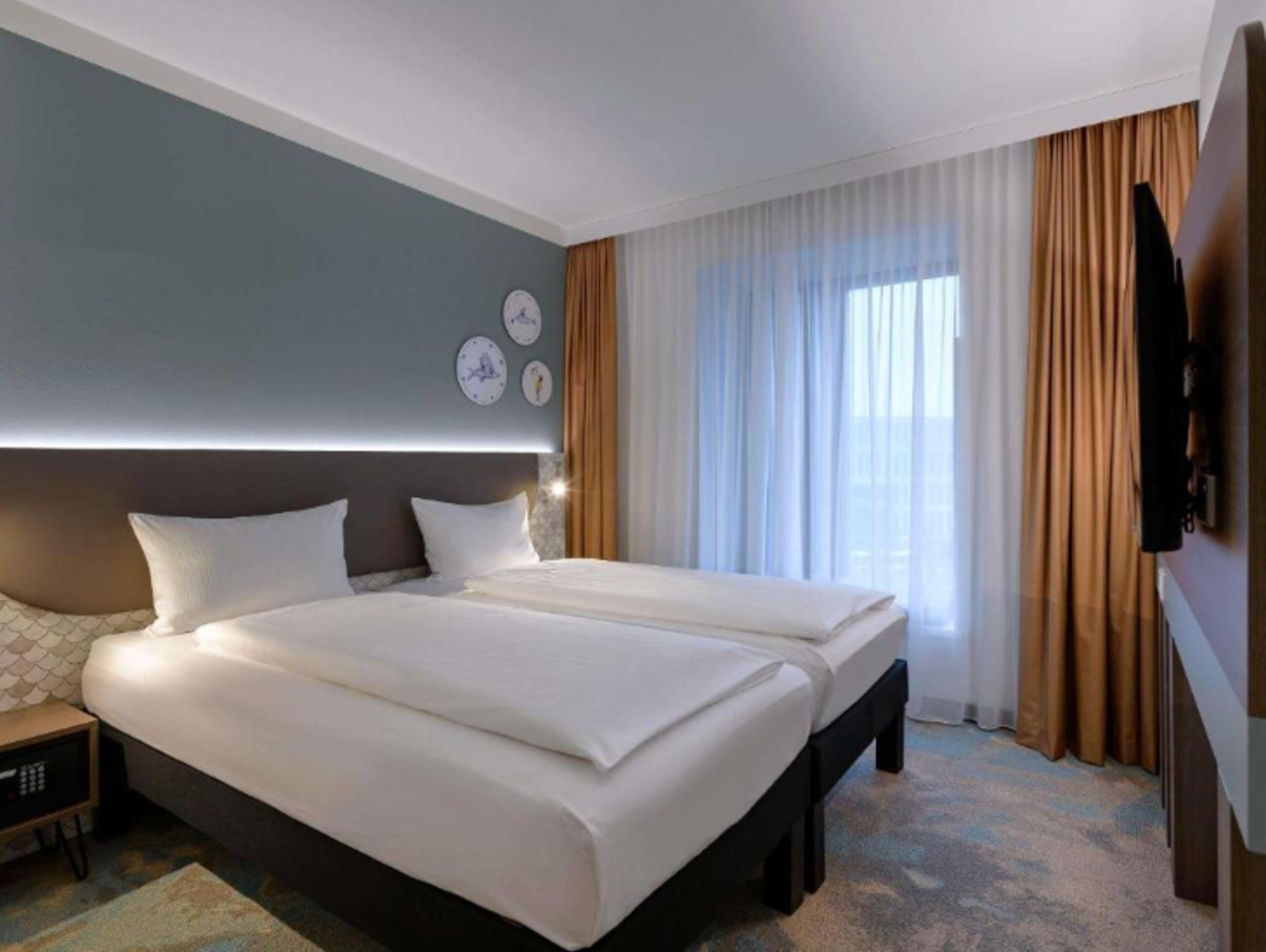 Modern eingerichtetes Doppelzimmer mit zwei Einzelbetten, großer Fensterfront mit Vorhängen, beruhigenden Farben und stilvollen Wanduhren für eine entspannte Atmosphäre. Modern eingerichtetes Doppelzimmer mit zwei Einzelbetten, großer Fensterfront mit Vorhängen, beruhigenden Farben und stilvollen Wanduhren für eine entspannte Atmosphäre.