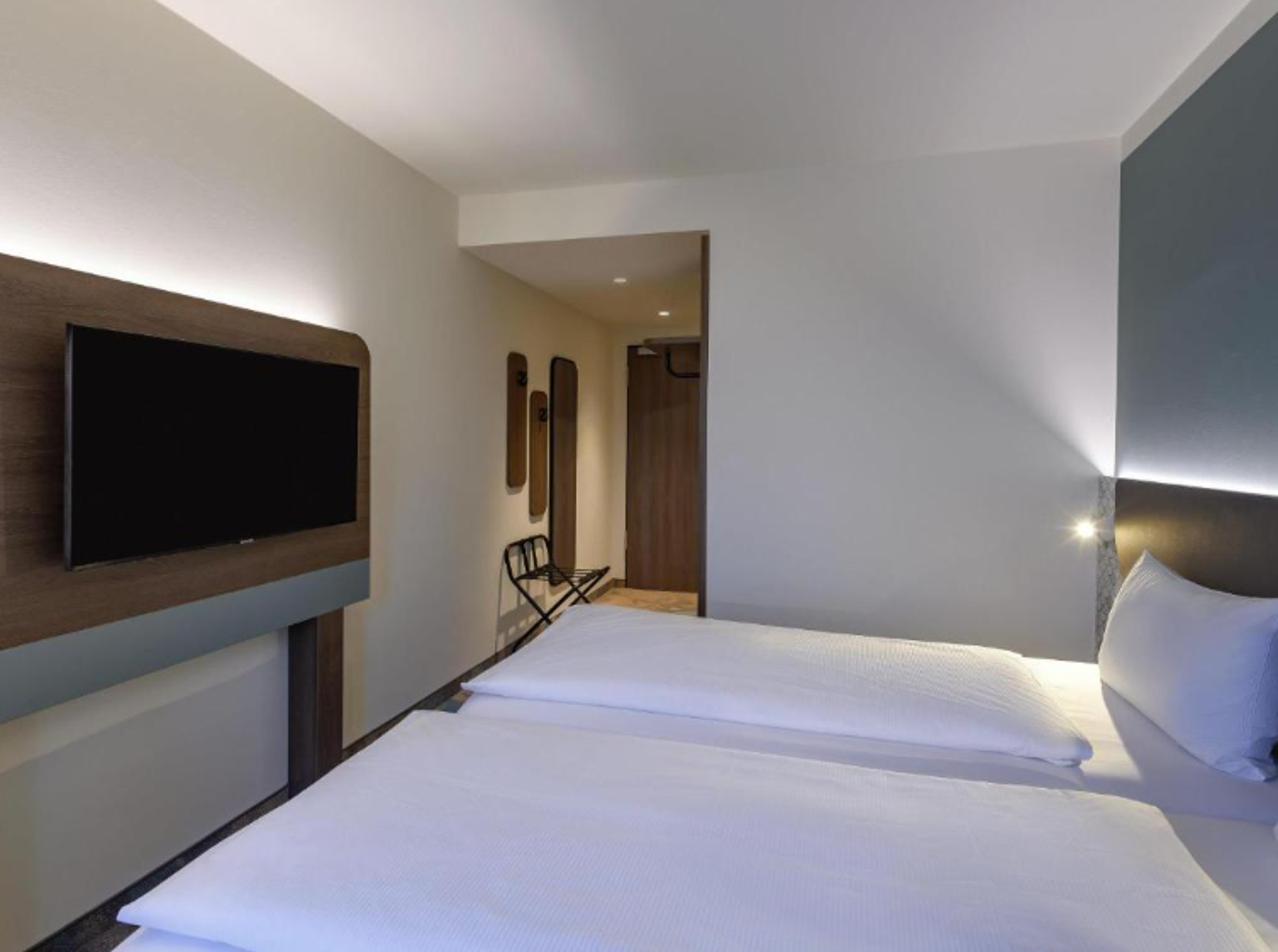 Modern eingerichtetes Hotelzimmer mit großem Bett, hellem Ambiente und Flachbildfernseher an der Wand, ideal für erholsamen Aufenthalt. Modern eingerichtetes Hotelzimmer mit großem Bett, hellem Ambiente und Flachbildfernseher an der Wand, ideal für erholsamen Aufenthalt.