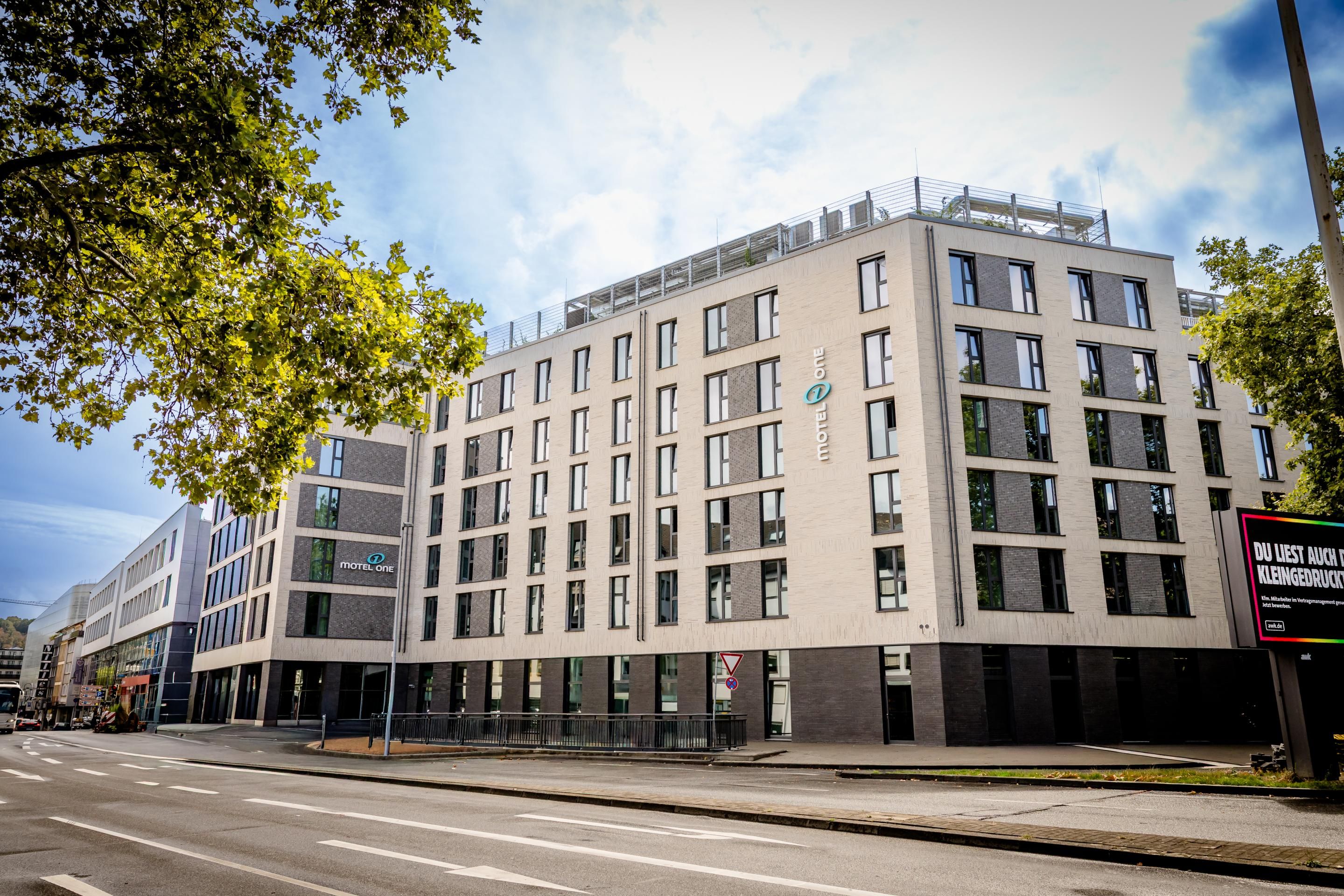 Modernes, mehrstöckiges Hotelgebäude mit großen Fenstern und klarer, heller Fassade an einer Stadtstraße. Das Hotel vermittelt ein urbanes, zeitgemäßes Ambiente für Geschäfts- und Freizeitgäste.