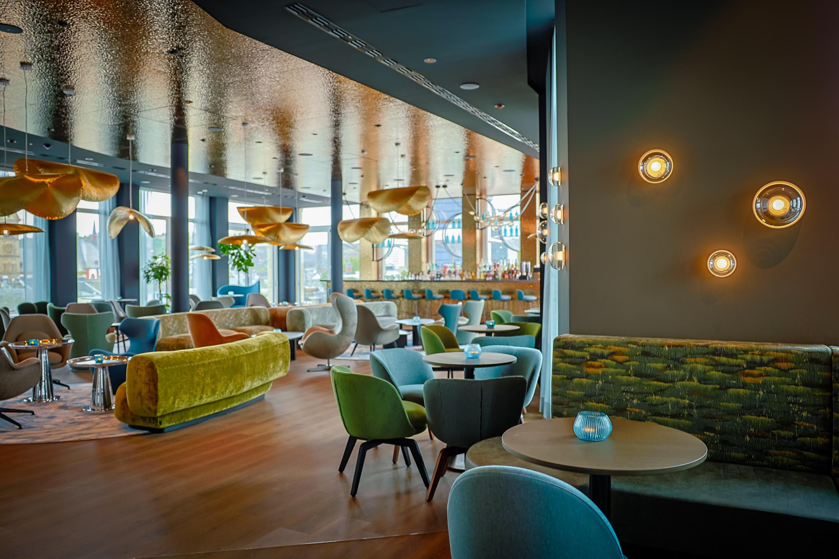 Moderner, stilvoll eingerichteter Lounge-Bereich mit bequemen Sesseln und Sofas, warmem Licht und großem Fenster für viel Tageslicht, ideal zum Entspannen und geselligen Beisammensein.