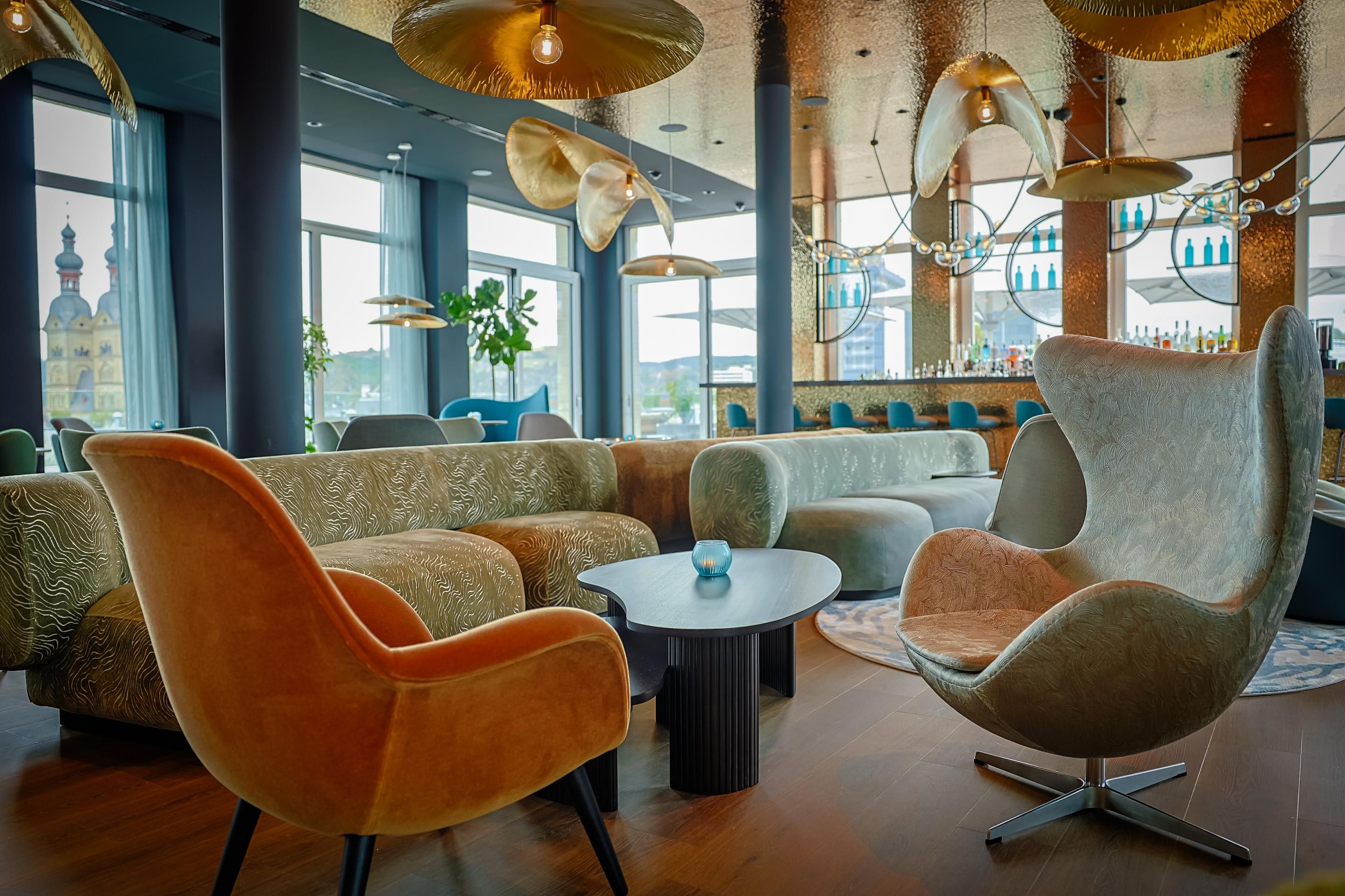 Gemütliche Lounge mit stilvollen Sesseln und Sofas, großen Fenstern mit Panoramablick, warmem Licht und modernem, einladendem Ambiente für entspannte Stunden.