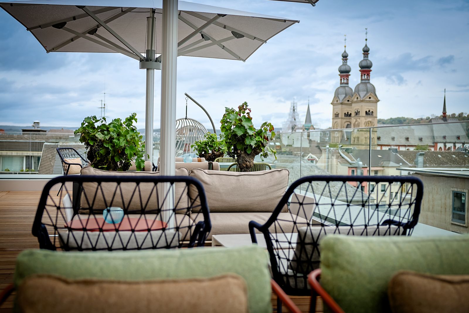 Dachterrasse mit gemütlichen Sitzgelegenheiten, Sonnenschirm und Blick auf die historische Stadtkulisse mit Kirchtürmen, ideal zum Entspannen und Genießen der Umgebung.