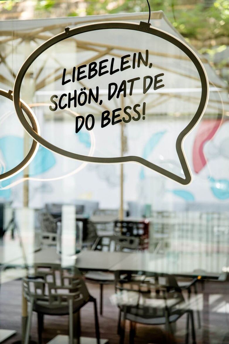 designhotel Cologne Mediapark Motel One slogan on glass pane with “Liebelein, schön, dat de do bess!”