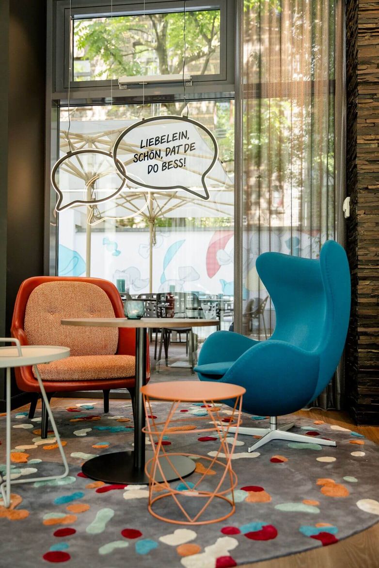 designhotel Cologne Mediapark Motel One two armchairs in front of large glass pane with decoration in the form of speech bubbles