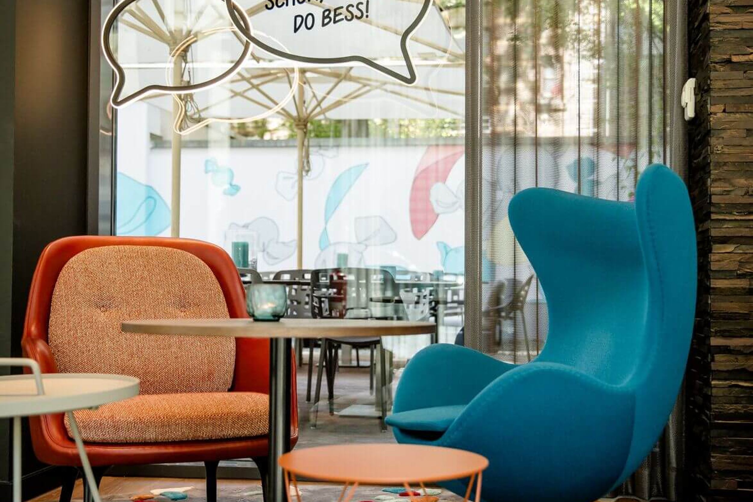 Designhotel Köln Mediapark Motel One zwei Sessel vor großer Glasscheibe mit Dekoration in Form von Sprechblasen