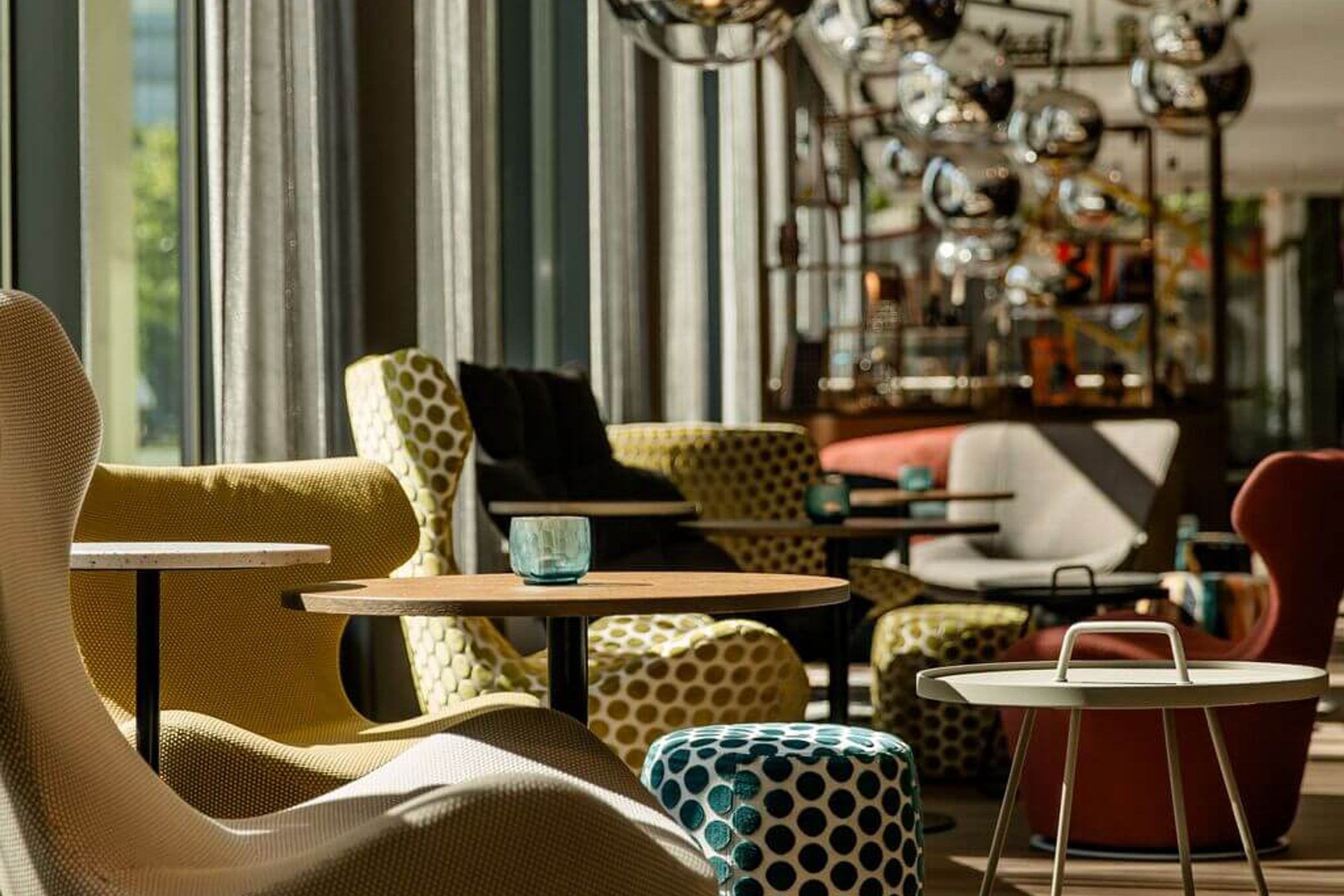 Hotel Köln Mediapark Motel One lichtdurchflutete Lounge mit Sesseln und großen silbernen Lampen