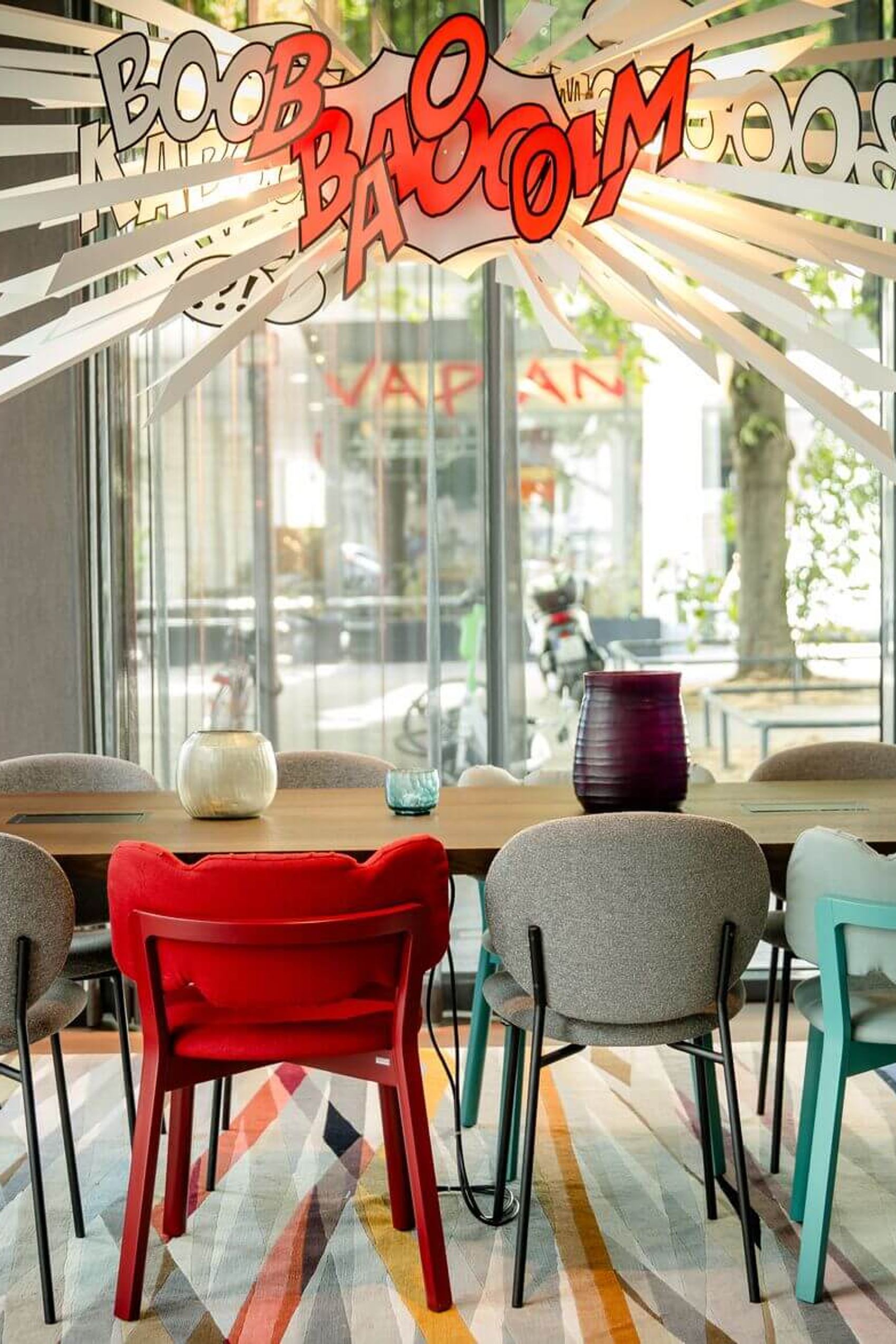 Designhotel Köln Mediapark Motel One lichtdurchfluteter Meetingraum mit Tisch, acht Stühlen und dekorativer Comic-Lampe