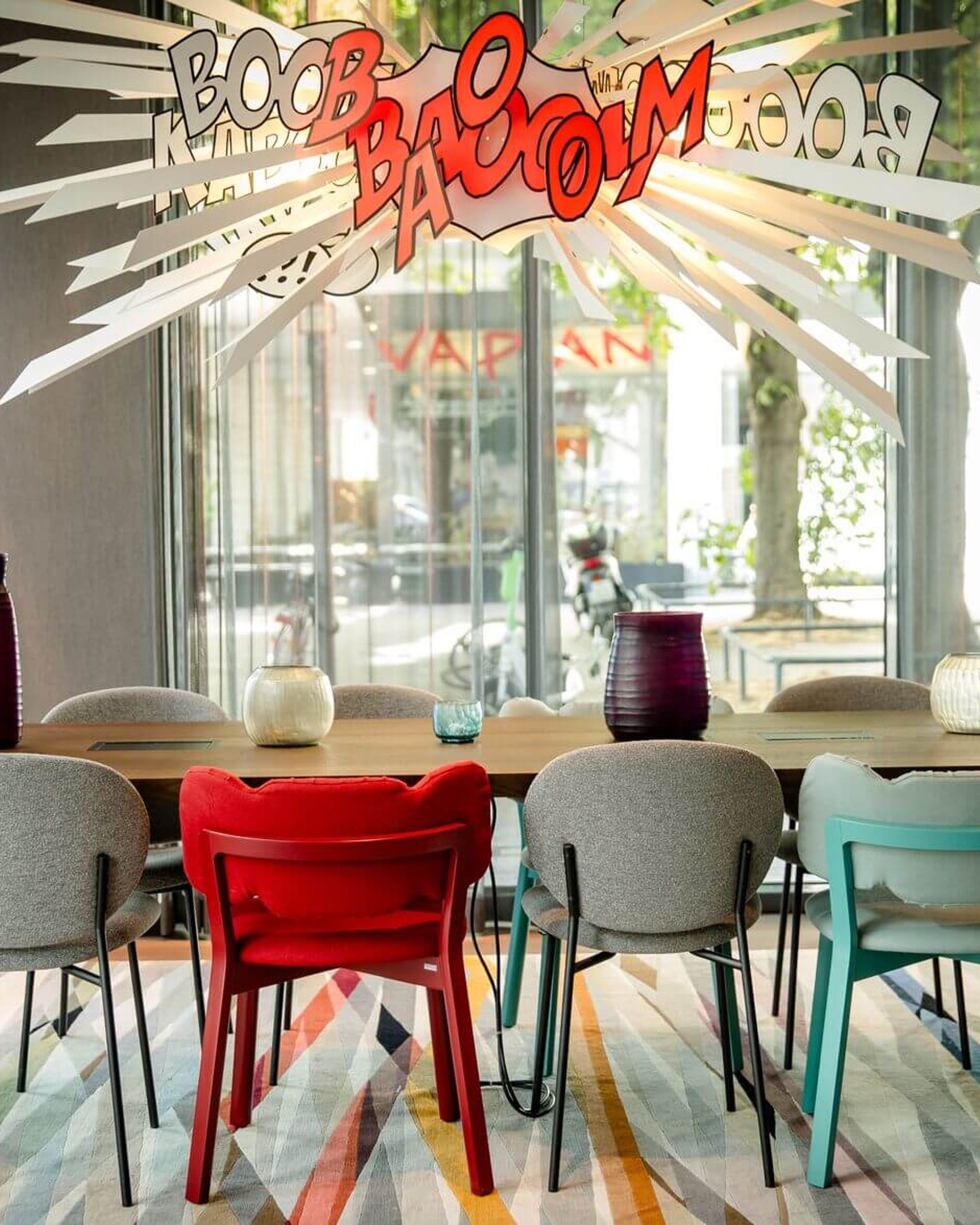 Designhotel Köln Mediapark Motel One lichtdurchfluteter Meetingraum mit Tisch, acht Stühlen und dekorativer Comic-Lampe