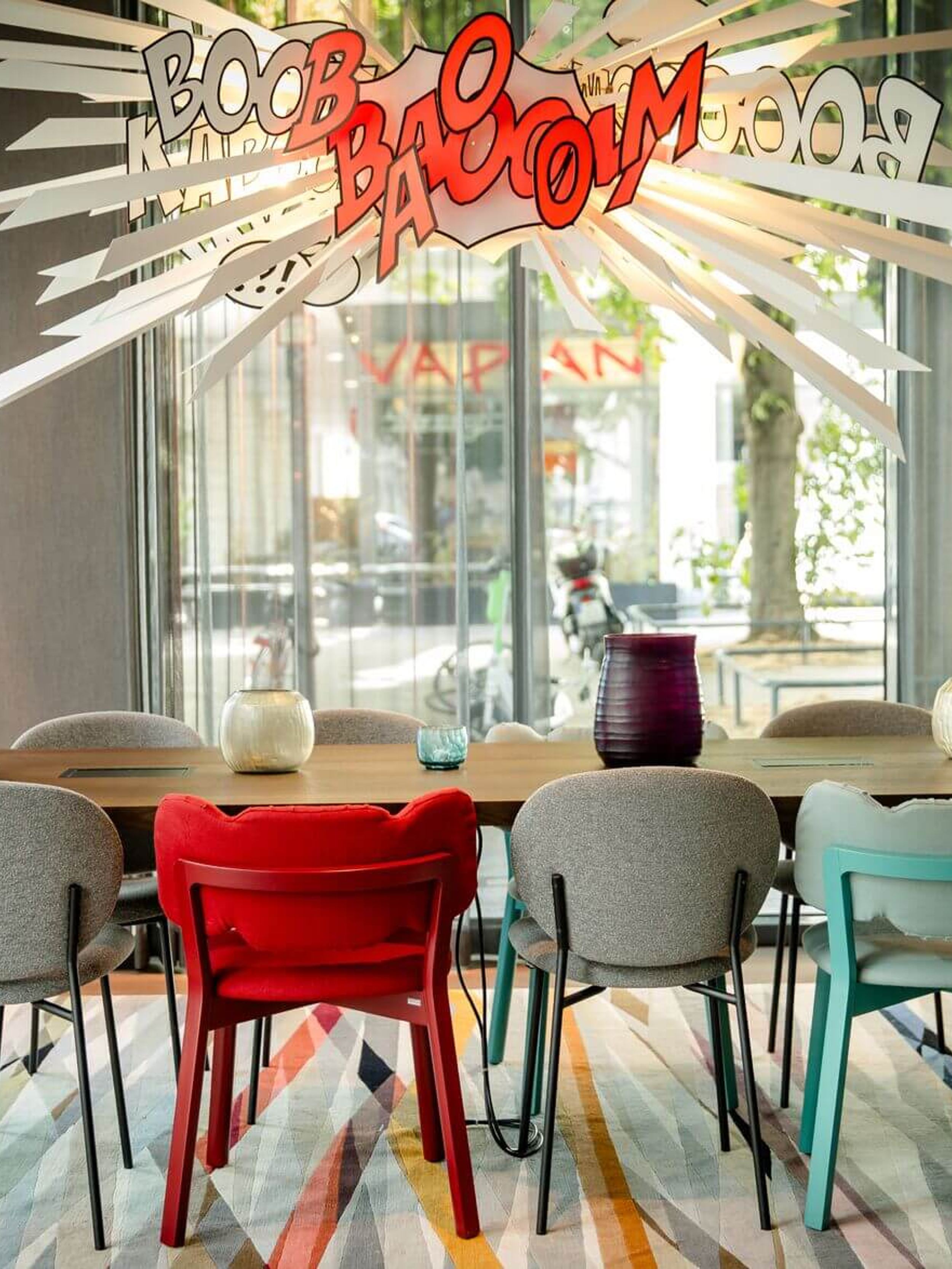 Designhotel Köln Mediapark Motel One lichtdurchfluteter Meetingraum mit Tisch, acht Stühlen und dekorativer Comic-Lampe