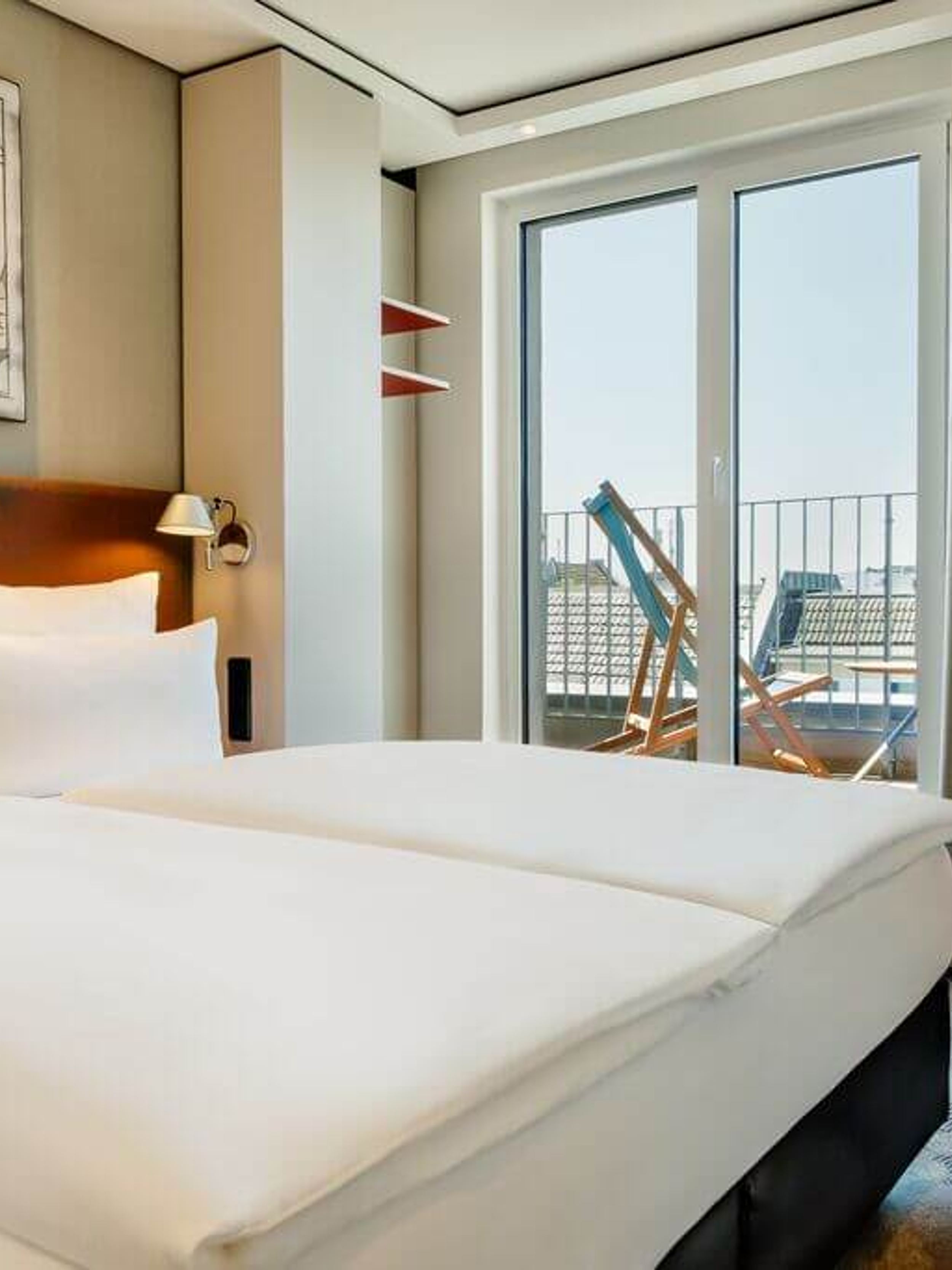 Hotel Köln Mediapark Motel One Balkonzimmer mit großem Doppelbett und Liegestuhl auf dem Balkon