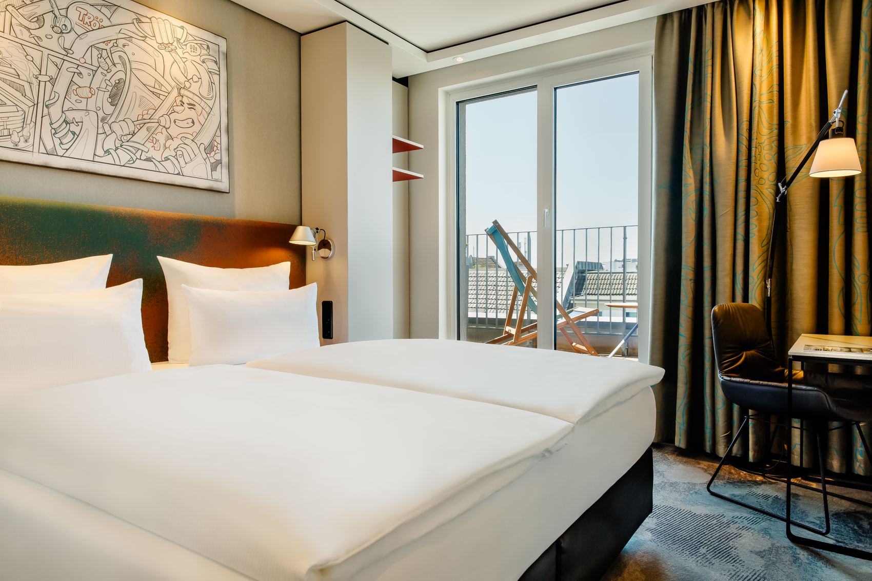 Designhotel Köln Mediapark Motel One lichtdurchflutetes Zimmer mit Bett, Schreibtisch, Sessel sowie bodentiefem Fenster