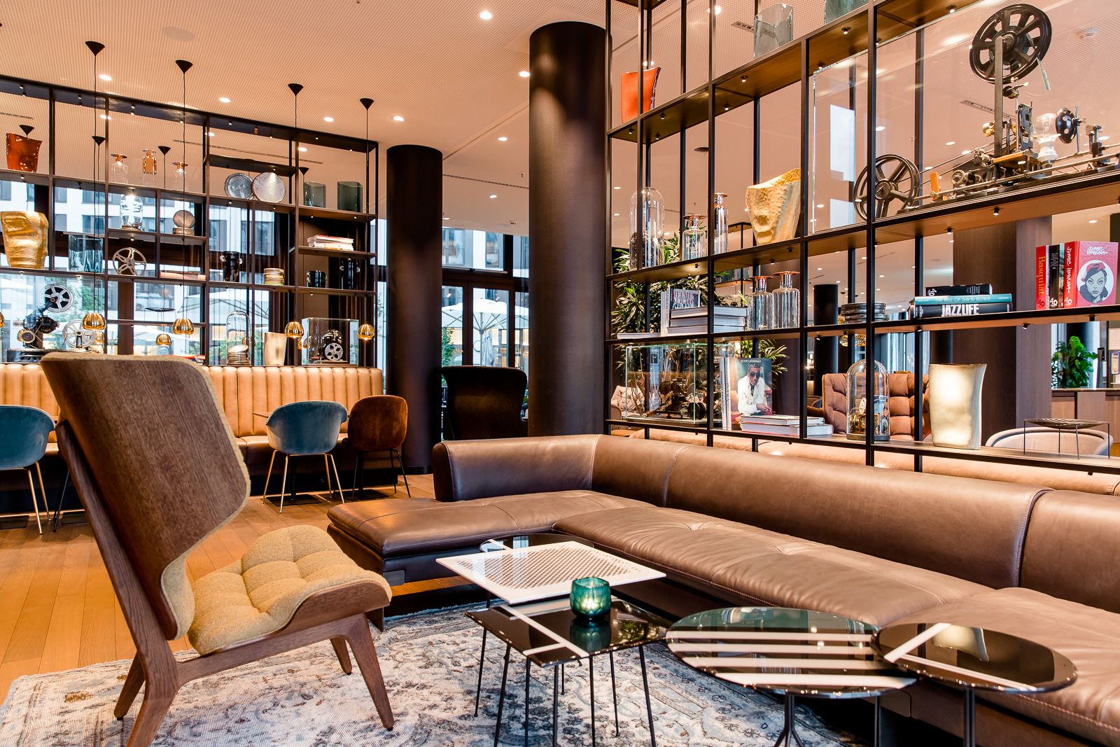 Designhotel Köln Messe Motel One Lounge mit offenen Regalen sowie mit Sesseln und großer Couch