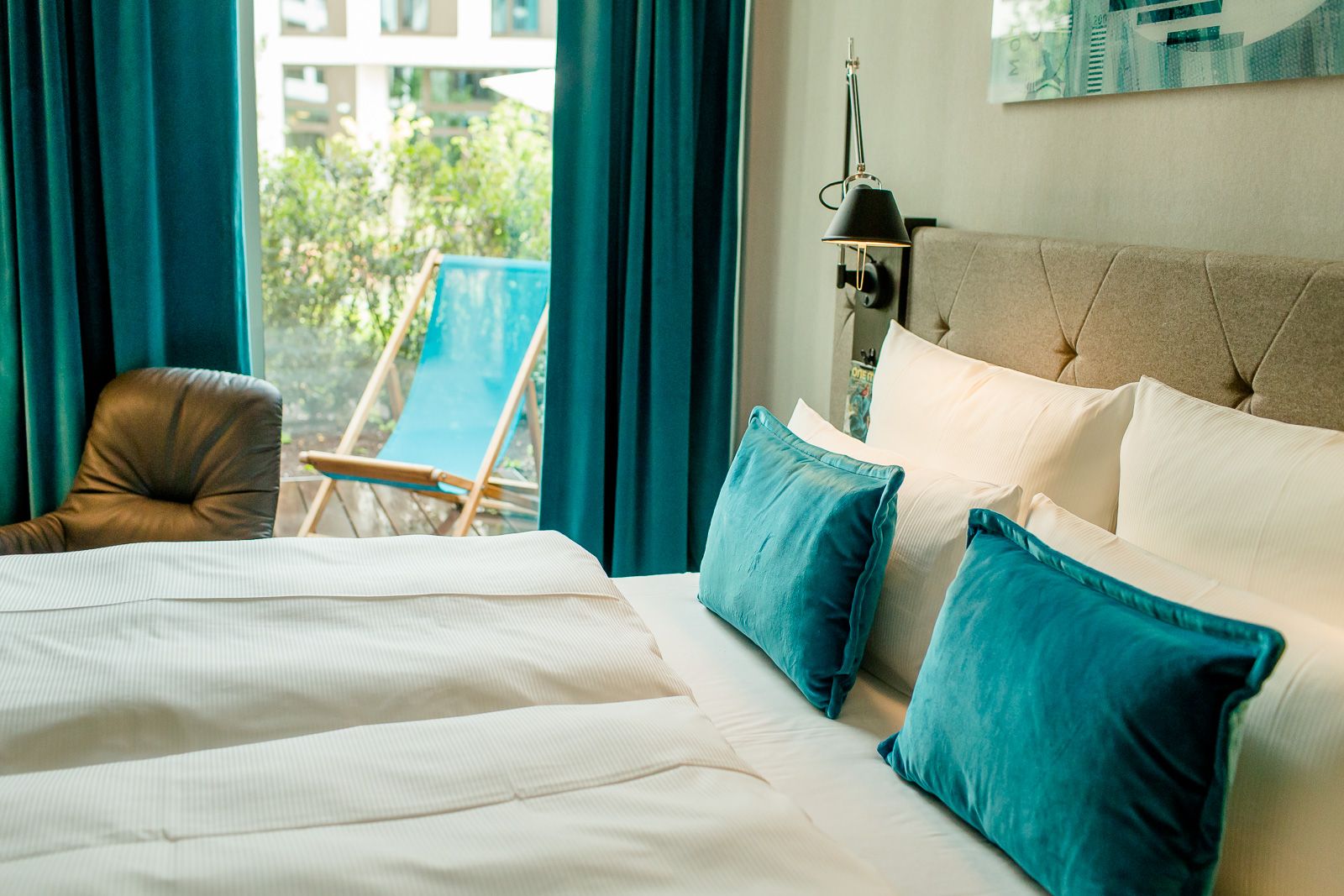 Designhotel Köln Messe Motel One Zimmer mit großem Bett sowie Balkonzugang und Liegestuhl