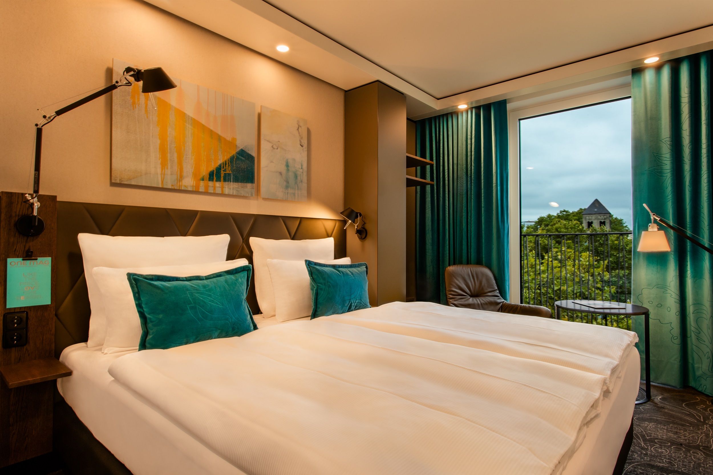 designhotel Cologne Neumarkt Motel One comfortable double bed and armchair in front of floor-to-ceiling window