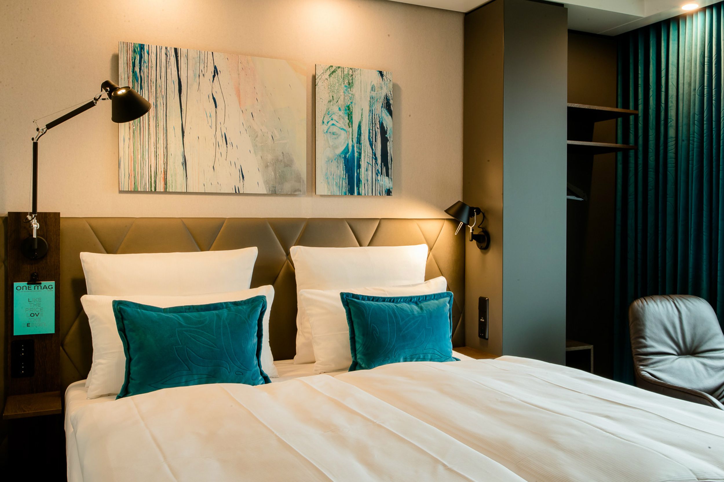 Hotel Köln Neumarkt Motel One Blick auf komfortables Bett mit Zierkissen in türkis
