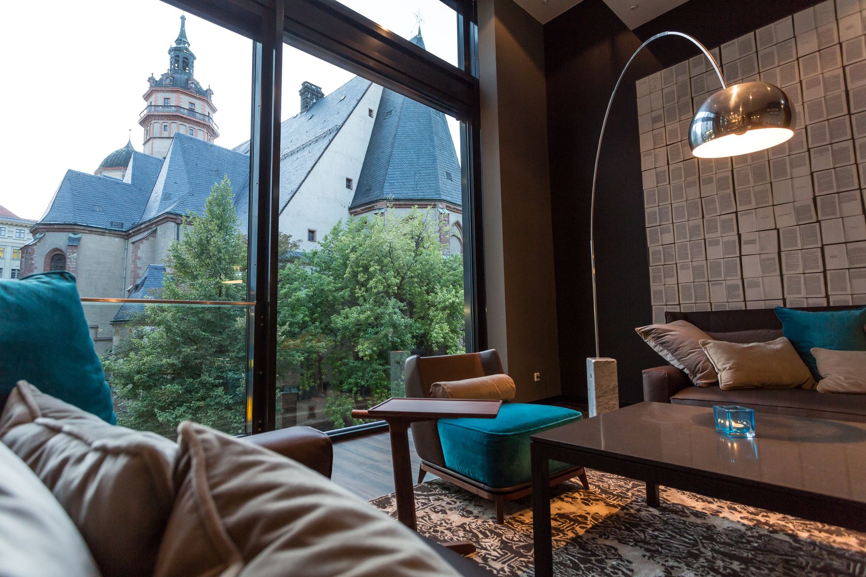 Hotel Leipzig Augustusplatz Motel One Blick über die Couch durch bodentiefes Fenster auf Kirche