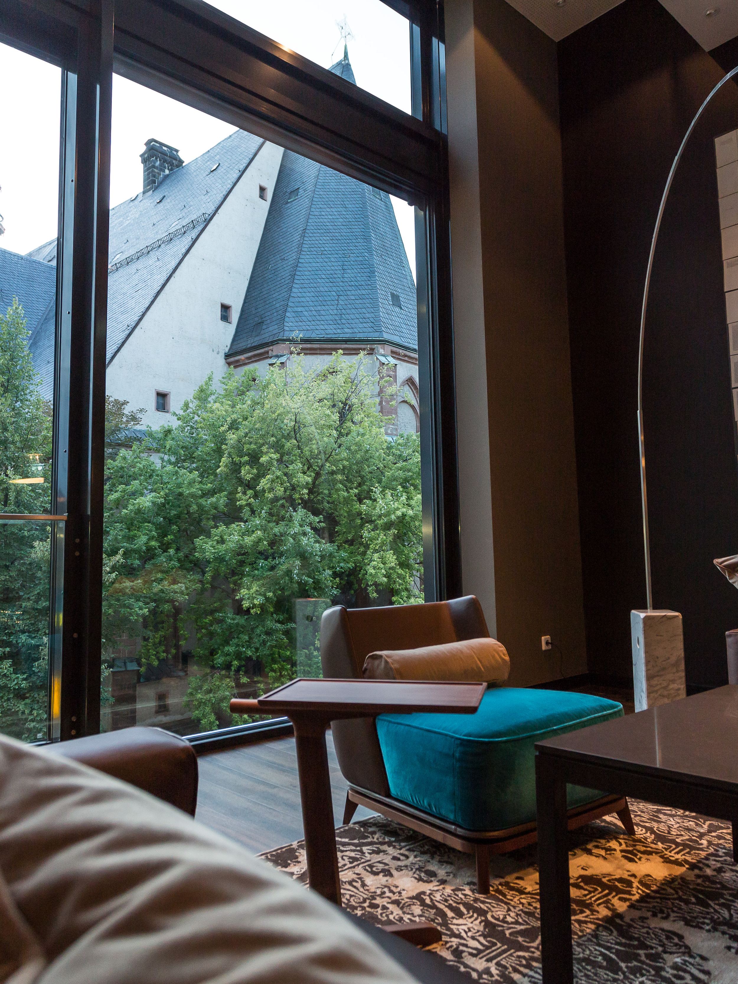 Hotel Leipzig Augustusplatz Motel One Blick über die Couch durch bodentiefes Fenster auf Kirche