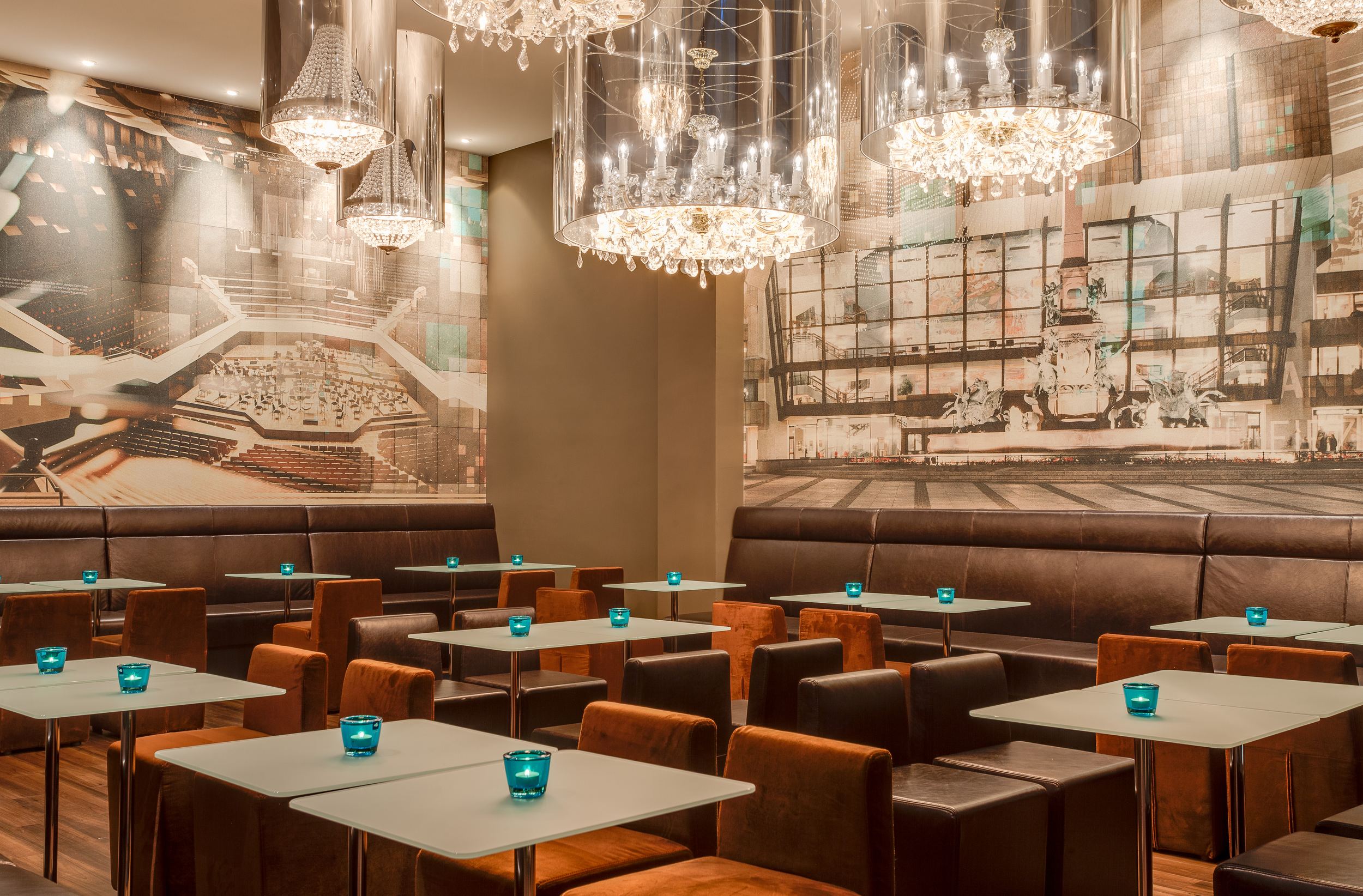 Hotel Leipzig Augustusplatz Motel One großer Raum mit Tischen und Stühlen sowie Gemälden an der Wand