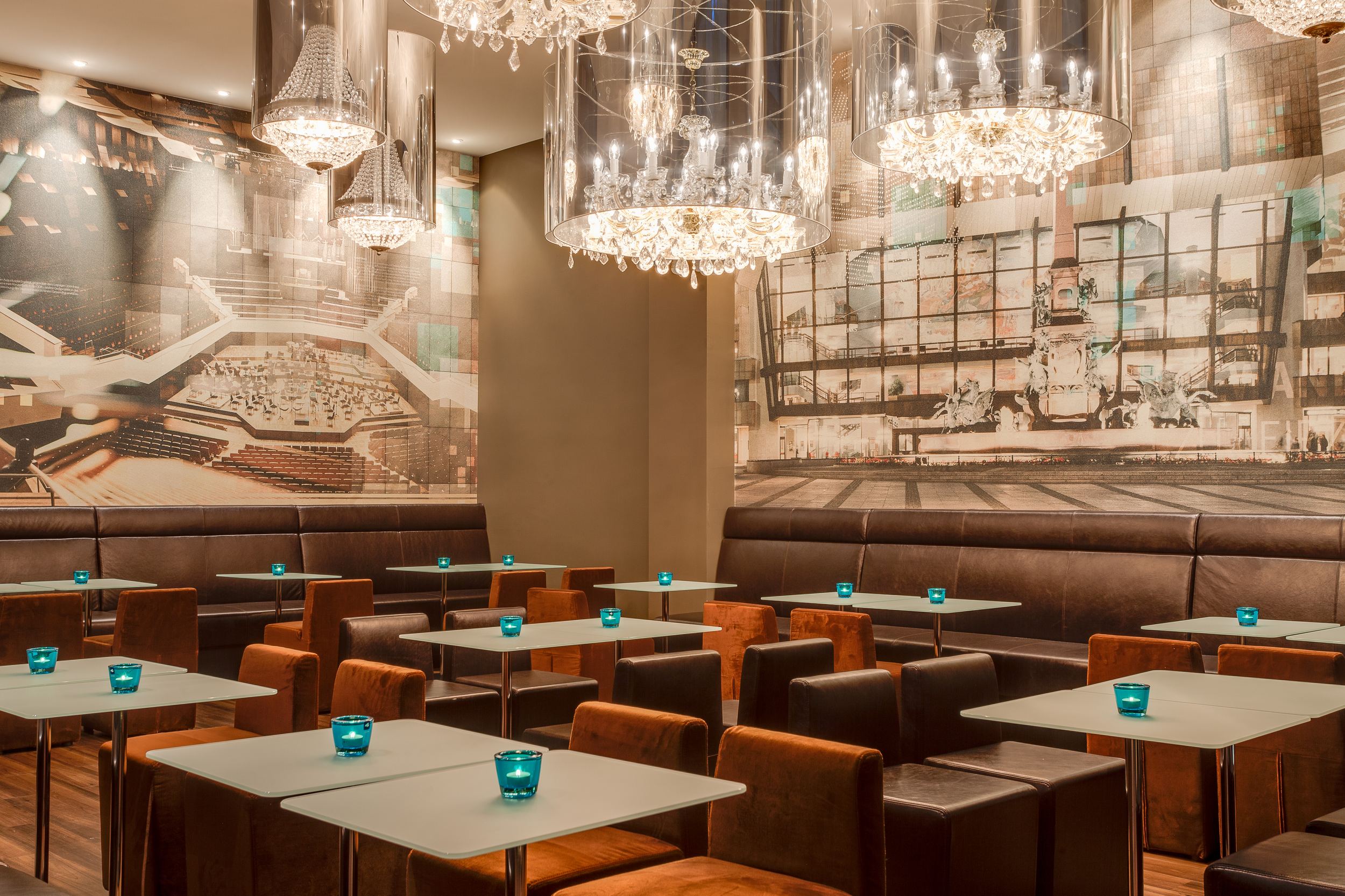 Hotel Leipzig Augustusplatz Motel One großer Raum mit Tischen und Stühlen sowie Gemälden an der Wand