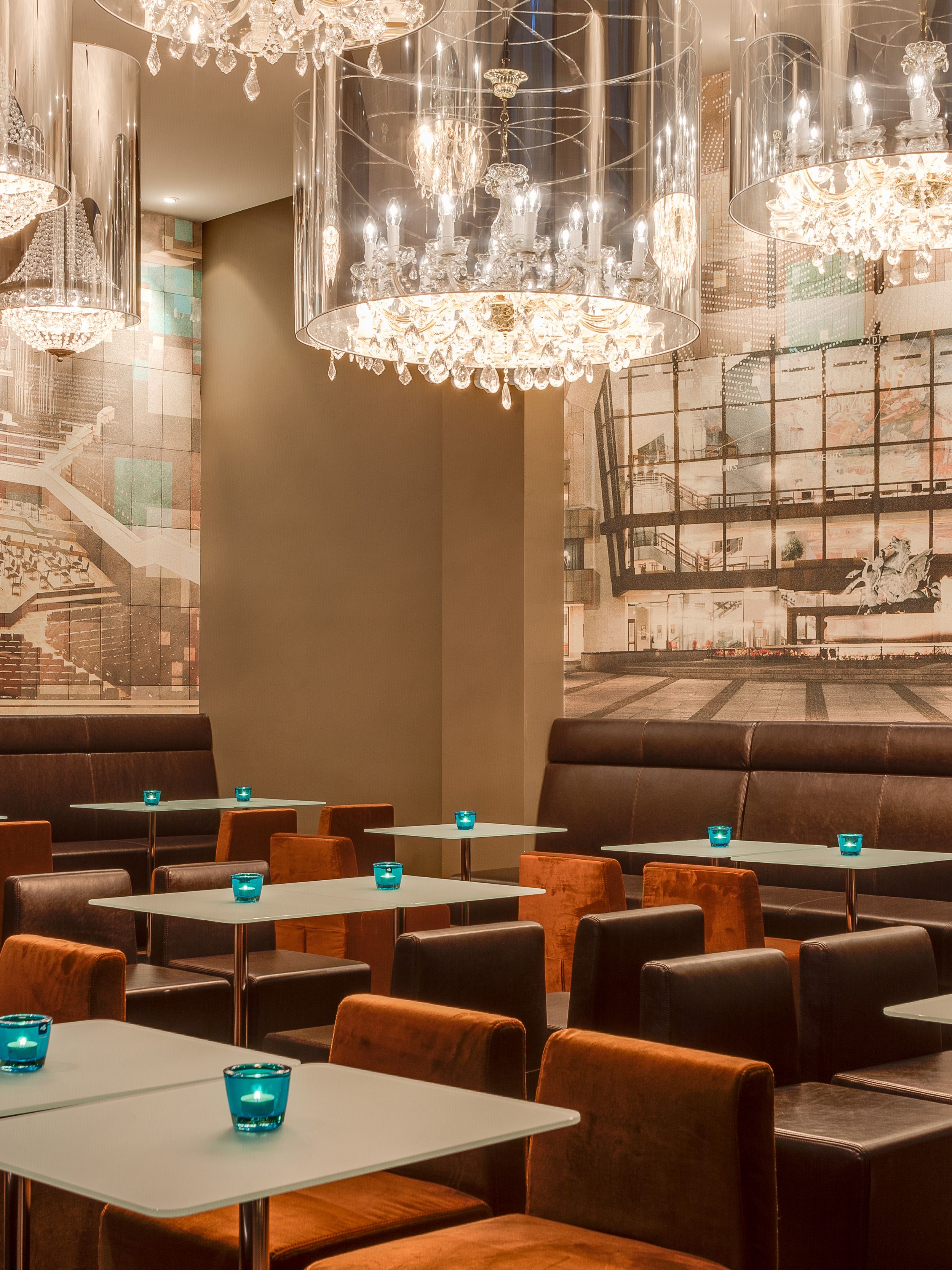 Hotel Leipzig Augustusplatz Motel One großer Raum mit Tischen und Stühlen sowie Gemälden an der Wand