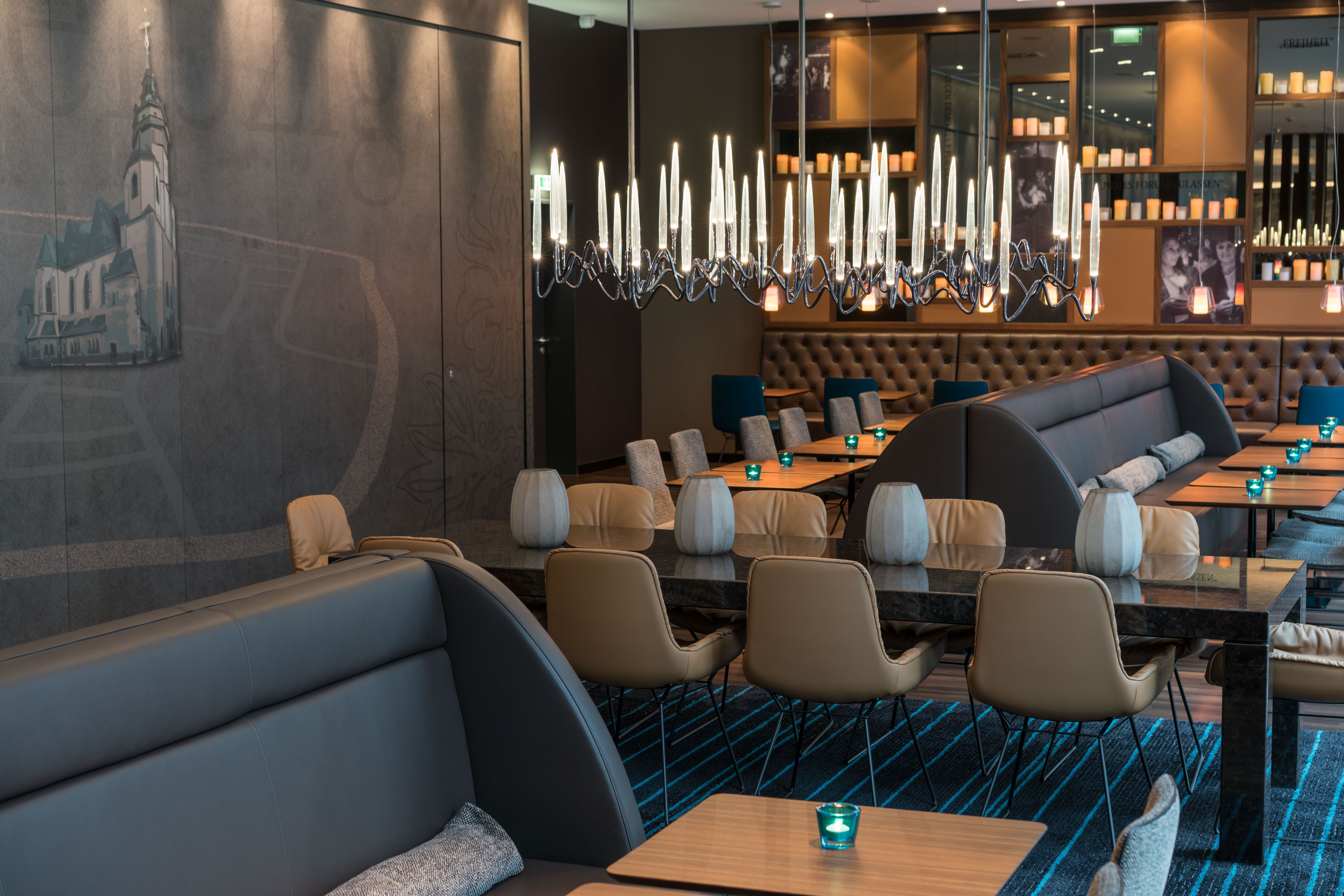 Designhotel Leipzig Nikolaikirche Motel One heller Raum mit mehreren Tischen und Stühlen