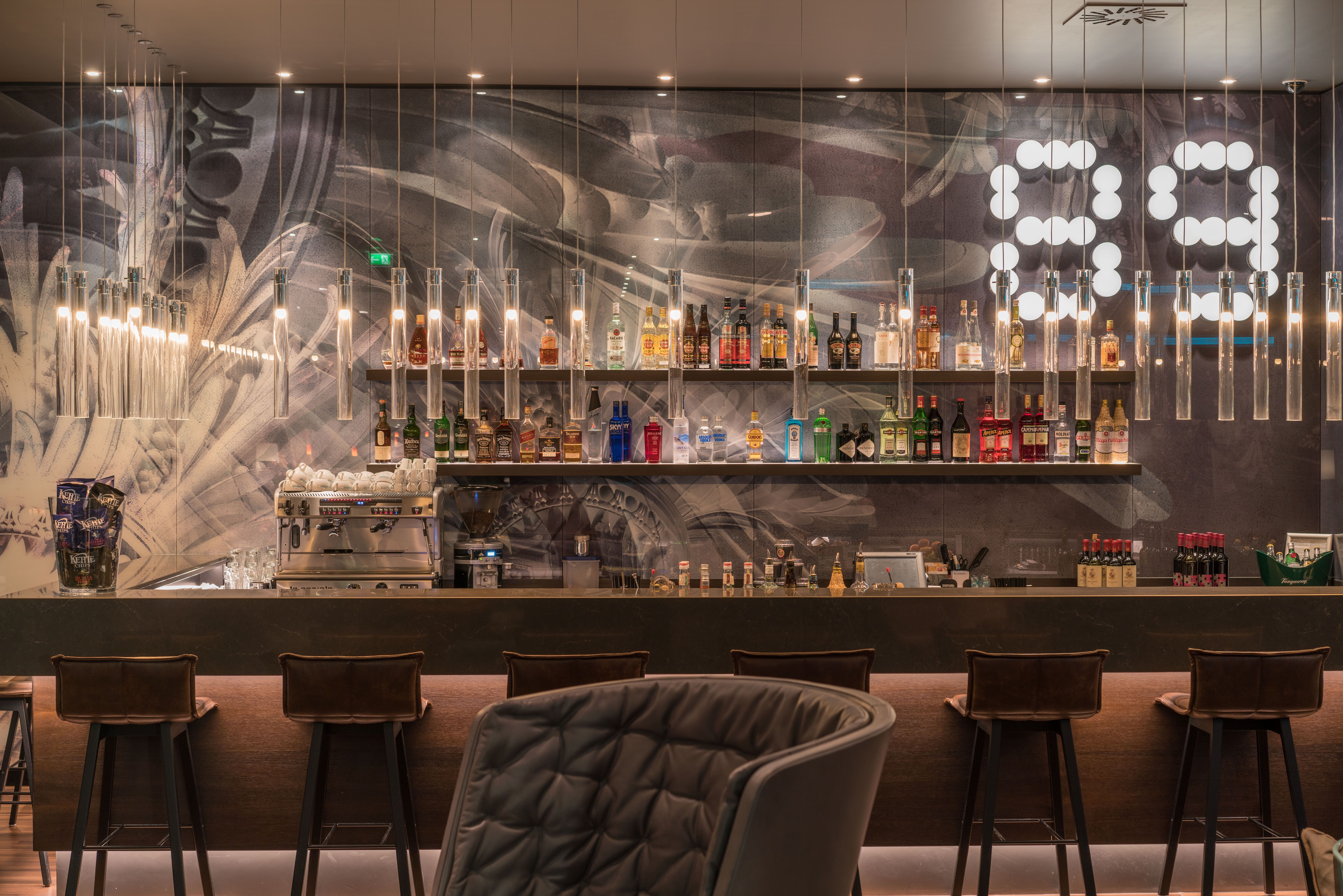 Hotel Leipzig Nikolaikirche Motel One Bar mit Barhockern vor dem Tresen sowie ein Sessel im Vordergrund