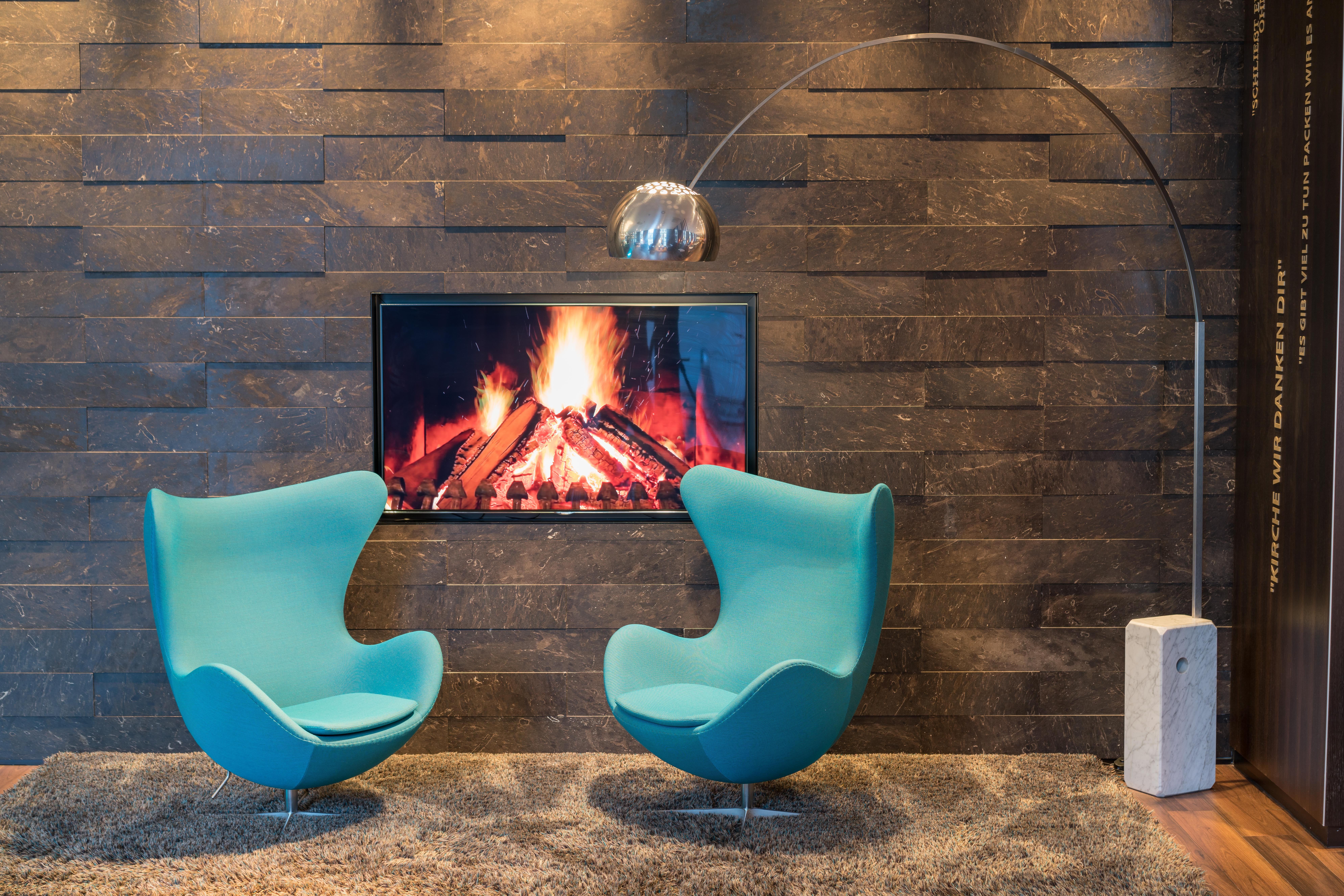 Hotel Leipzig Nikolaikirche Motel One zwei Egg chairs vor Fernseher, auf dem Lagerfeuer abgebildet ist