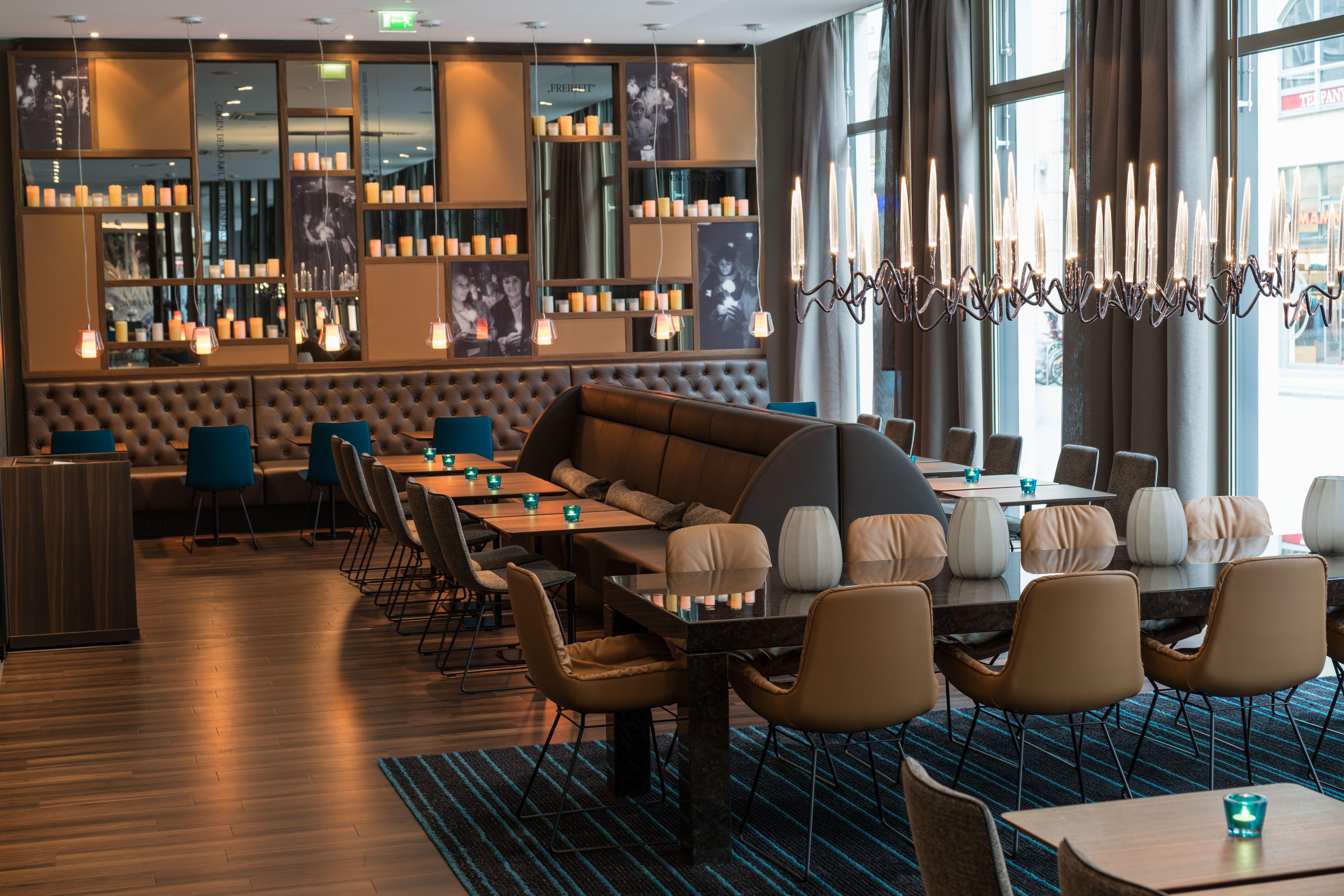 Hotel Leipzig Nikolaikirche Motel One heller Raum mit bodentiefen Fenstern sowie mit Tischen und Stühlen