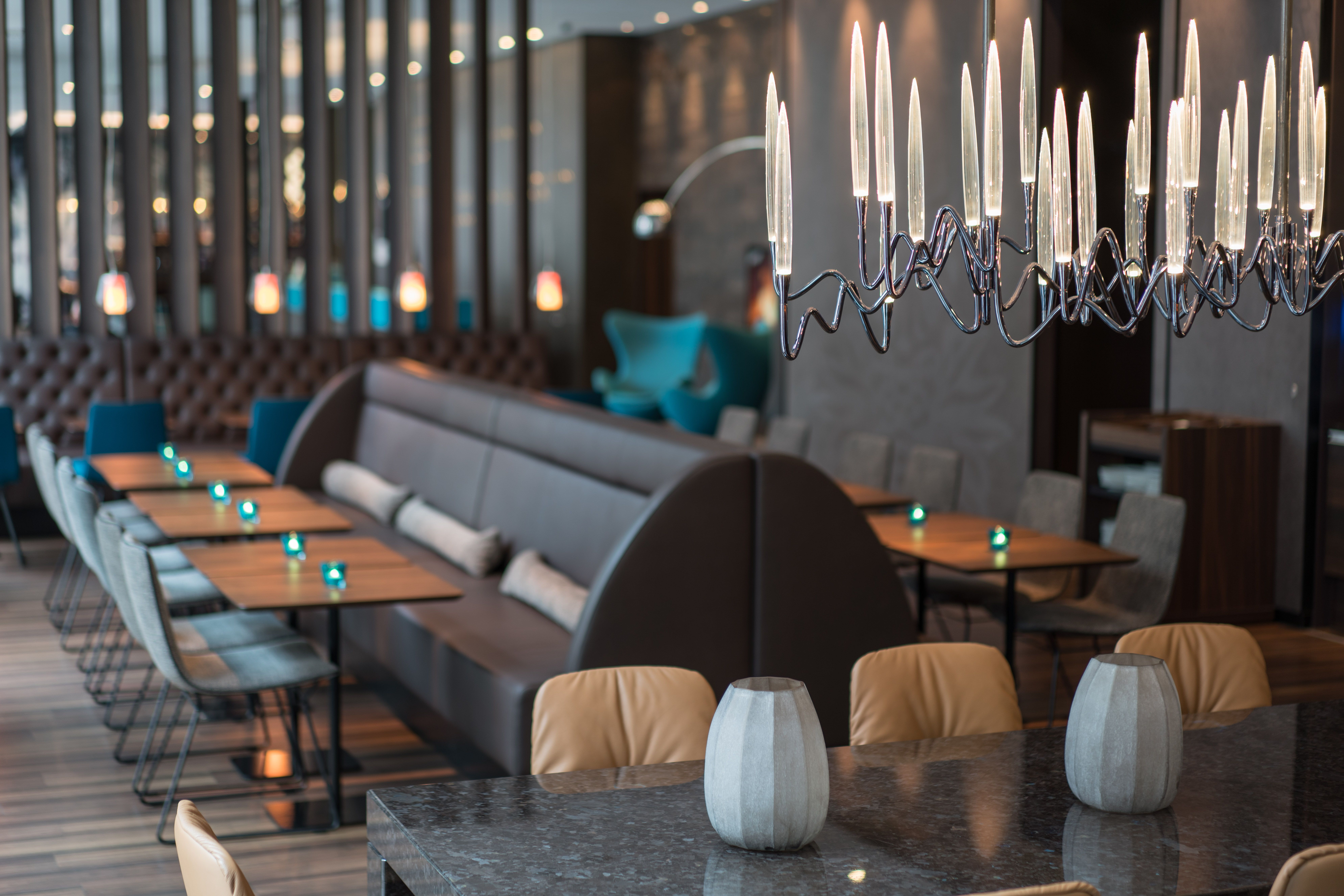 Hotel Leipzig Nikolaikirche Motel One Fokus auf helle Lampe über einem Tisch in großer Lounge