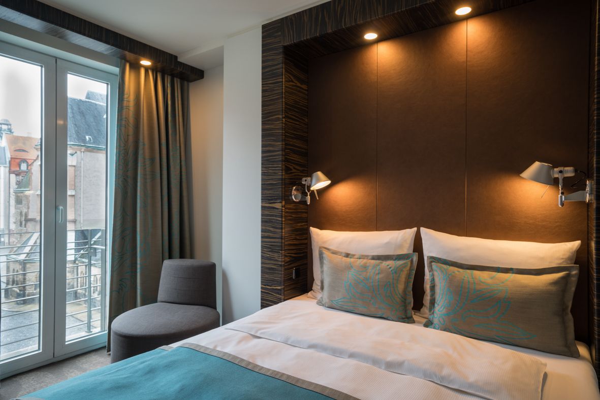 Designhotel Leipzig Nikolaikirche Motel One helles Zimmer mit Zierkissen auf komfortablem Doppelbett