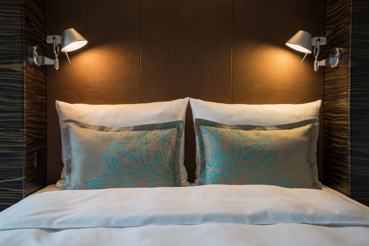 Designhotel Leipzig Nikolaikirche Motel One Doppelbett mit zwei weißen Kissen sowie zwei gemusterten Zierkissen