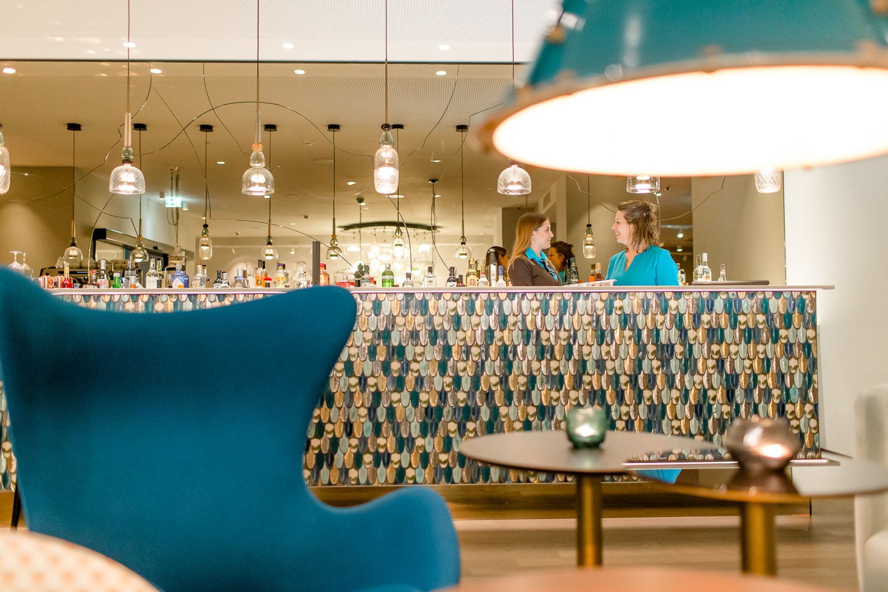 hotel Linz Hauptplatz Motel One bar with two employees and egg chair in the foreground