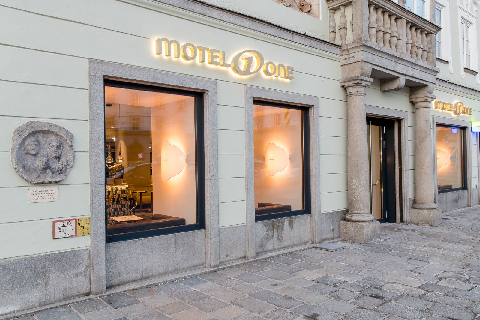 Hotel Linz Hauptplatz Motel One Blick auf den Eingangsbereich mit leuchtendem Logo