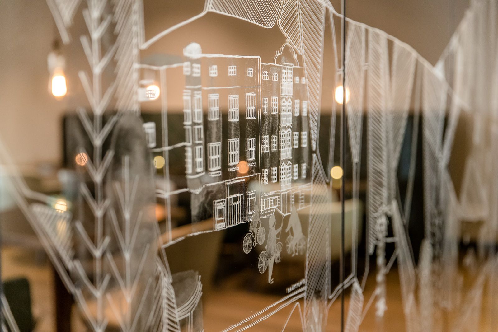 Designhotel Linz Hauptplatz Motel One Nahaufnahme Zeichnung von Häusern in weiß auf Glas