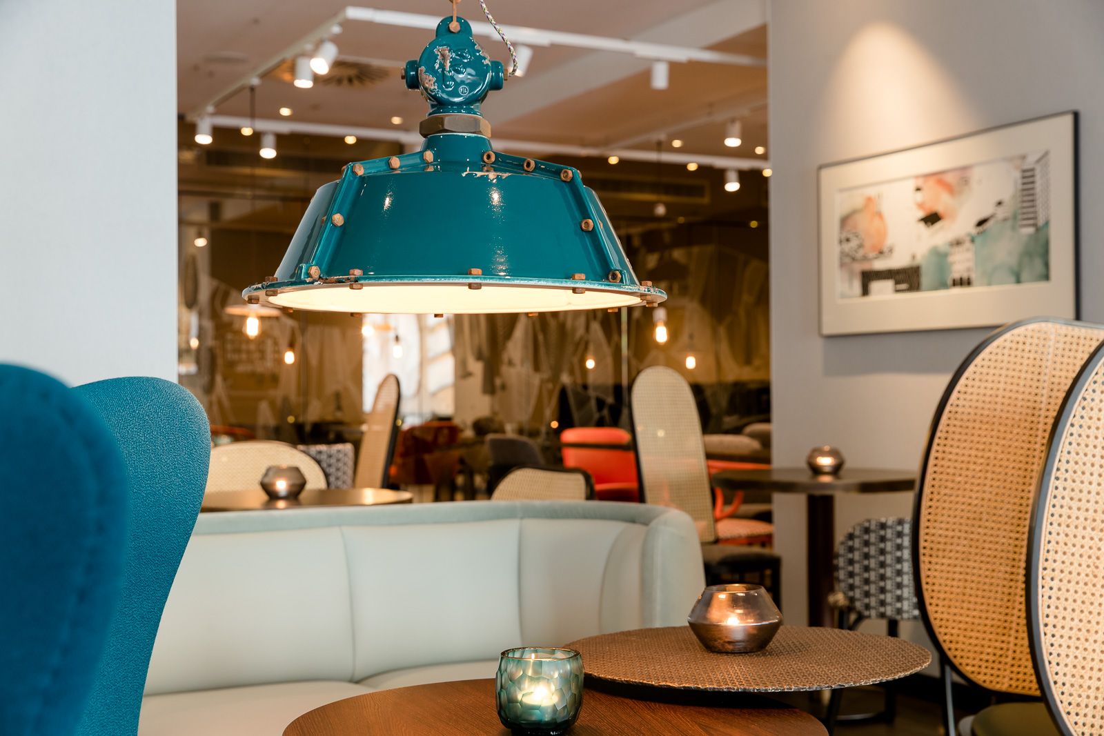 Designhotel Linz Hauptplatz Motel One helle Lounge mit mehreren Sitzgelegenheiten sowie große Deckenlampe im Vordergrund