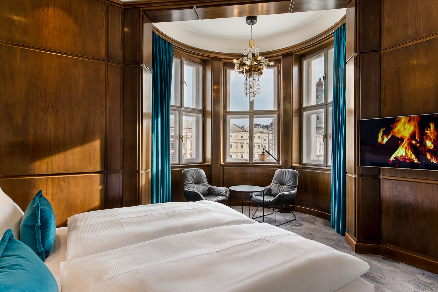 hotel Linz Hauptplatz Motel One large room with bed and a bay window with two chairs and table