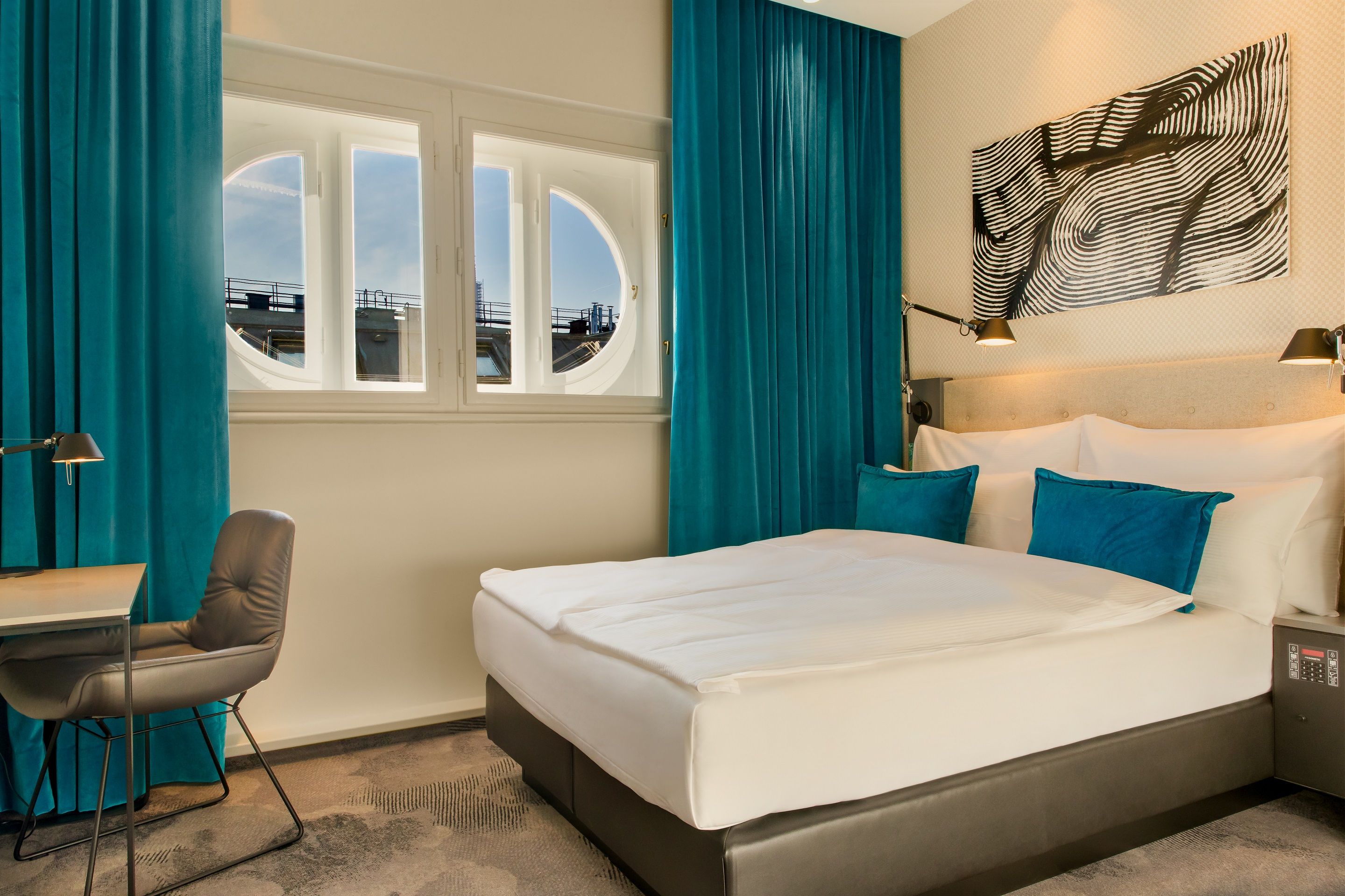 Hotel Linz Hauptplatz Motel One gemütliches Zimmer mit Doppelbett sowie Schreibtisch und Stuhl